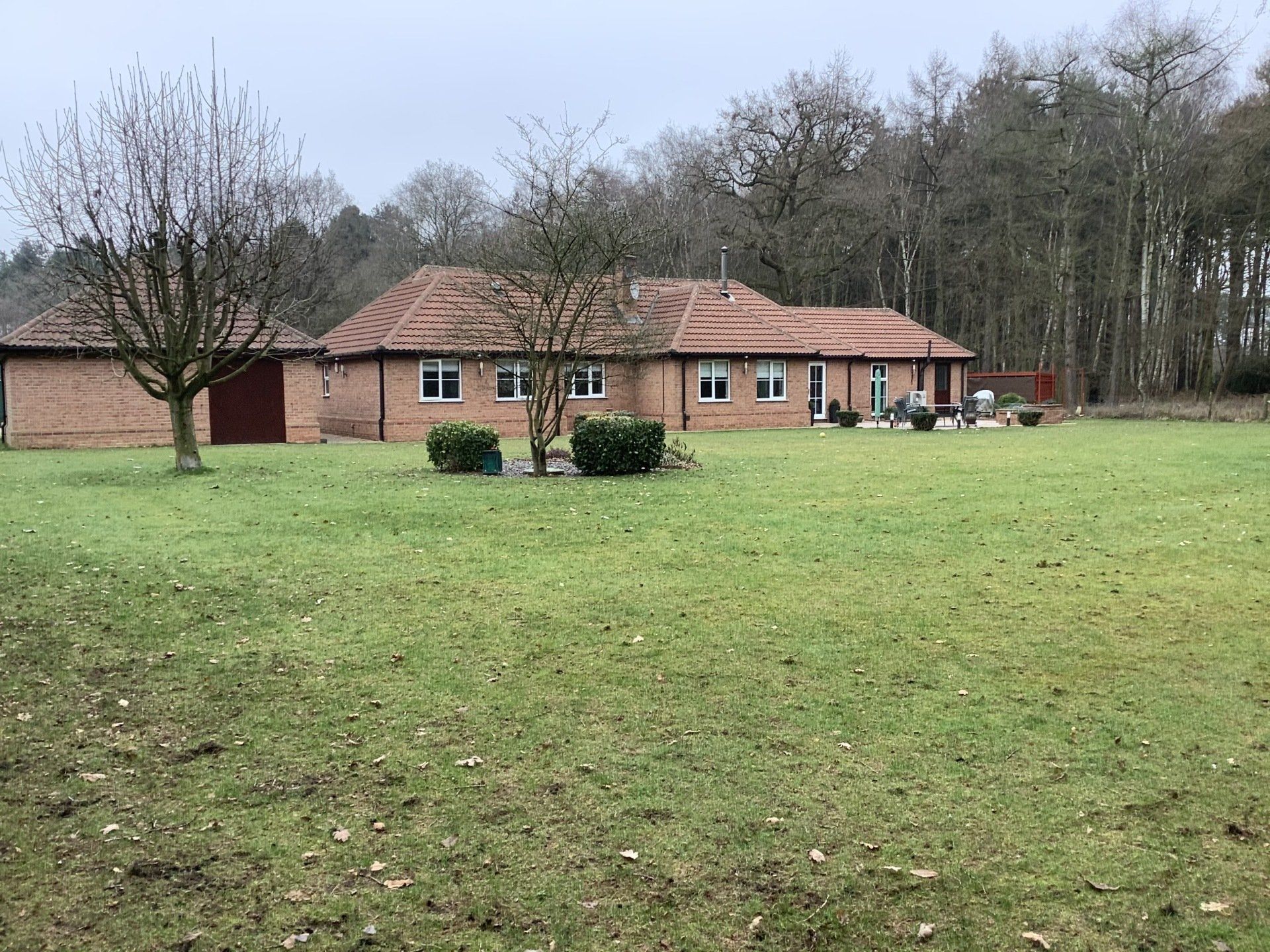 A large house is sitting in the middle of a grassy field.