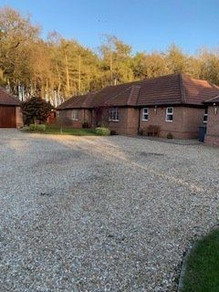 A large brick house with a gravel driveway in front of it.