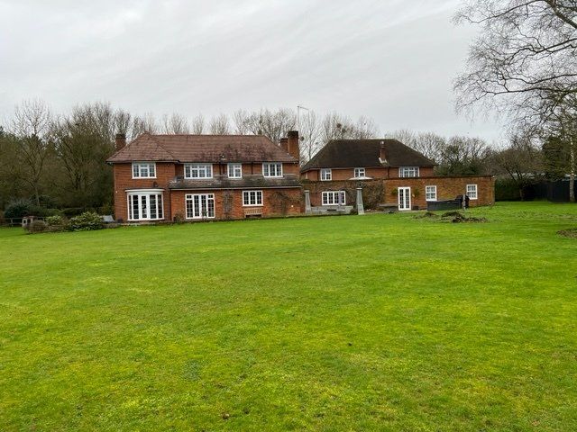 A large brick house is sitting on top of a lush green field.