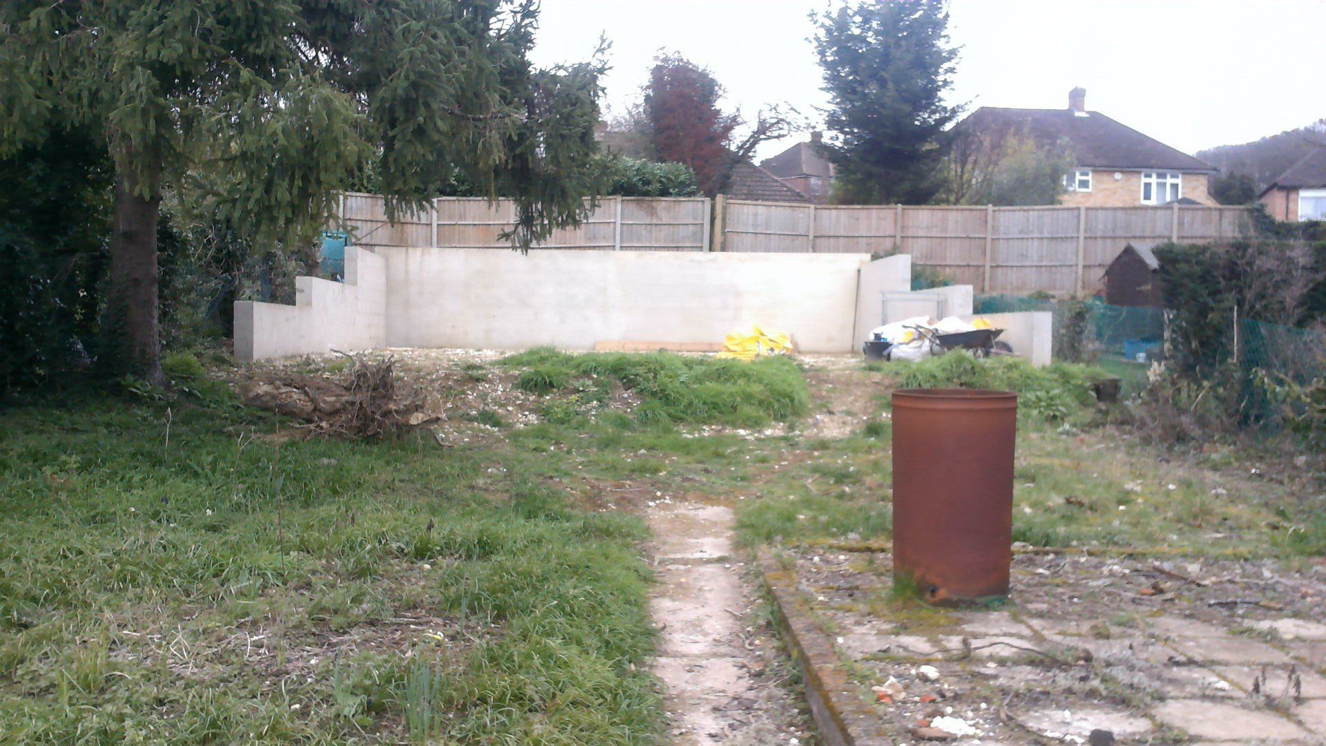 A backyard with a fence and a few houses in the background