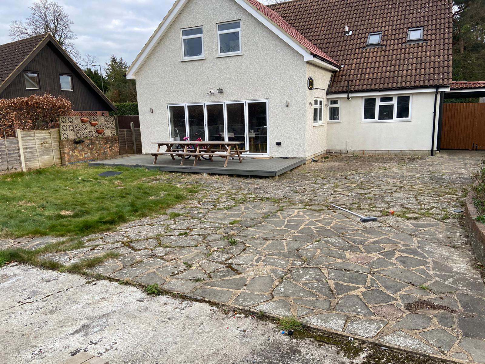 A white house with a red roof and a stone driveway in front of it.