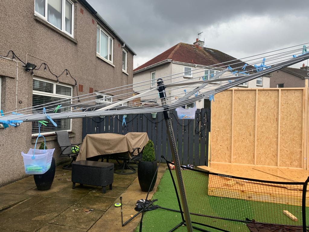 A clothes line is hanging outside of a house on a cloudy day.