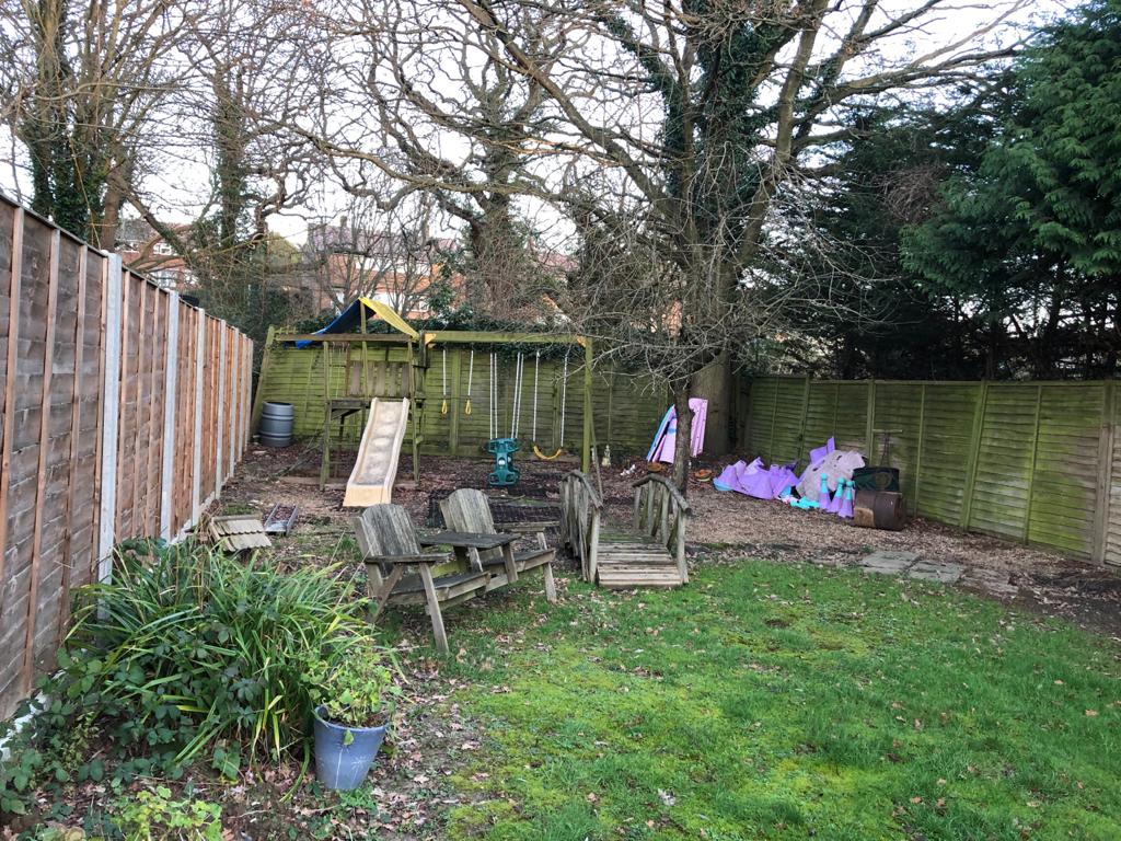 A backyard with a wooden fence and a playground.