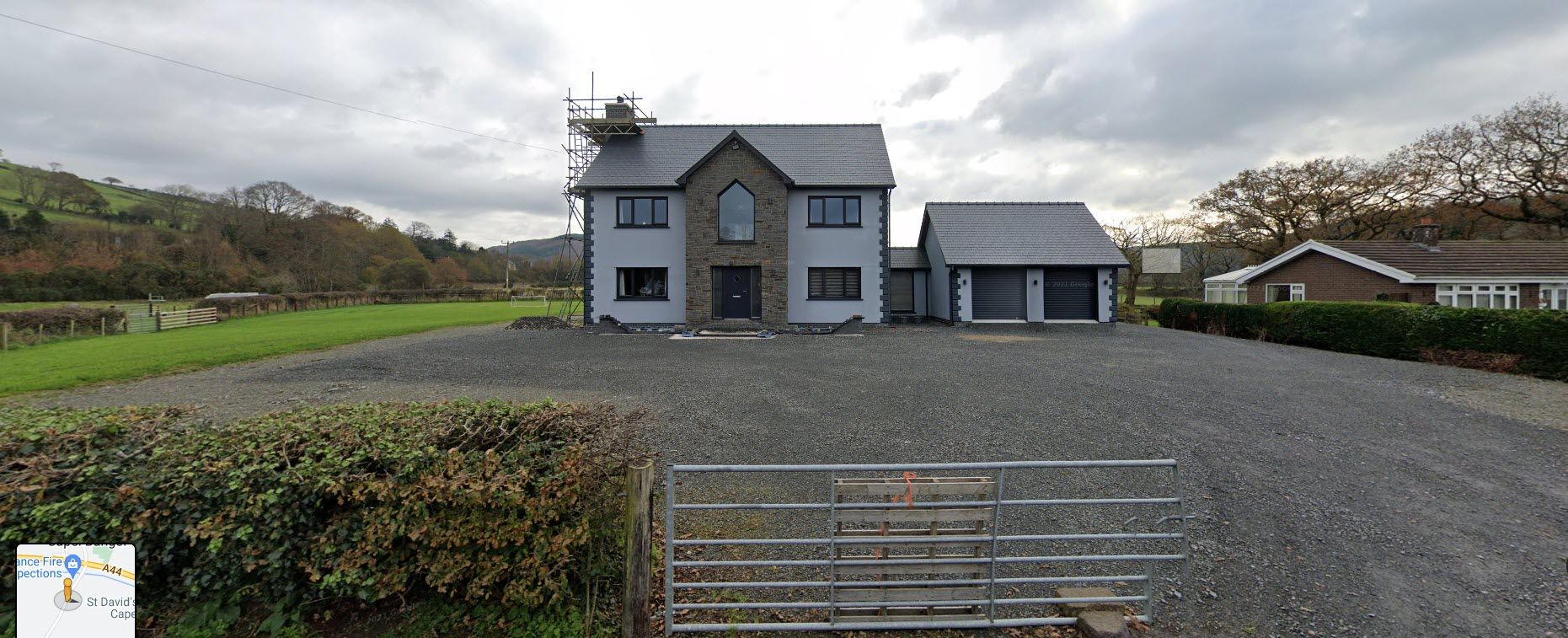 A large house with a gravel driveway in front of it.