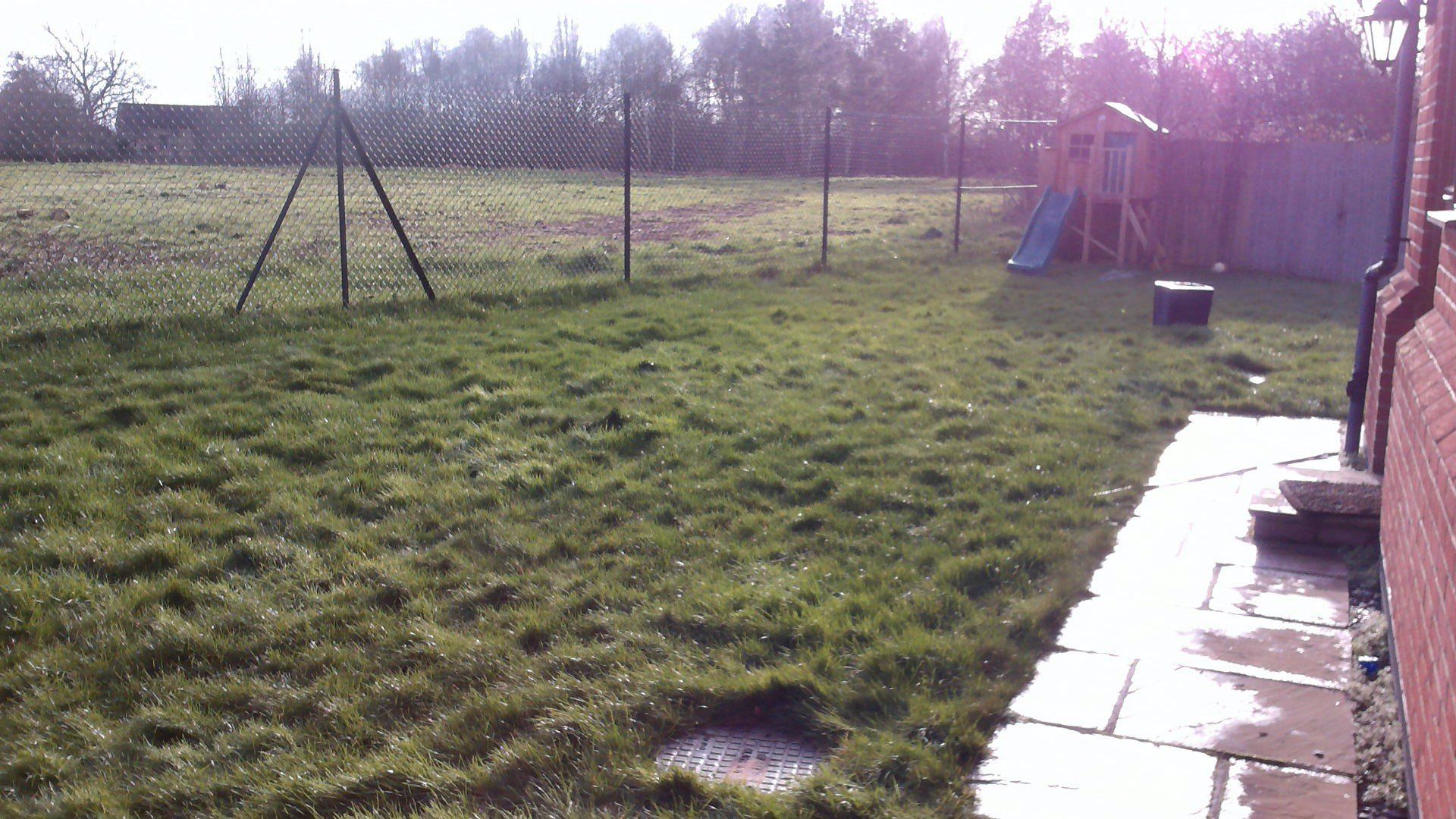 A fenced in yard with a playground in the background