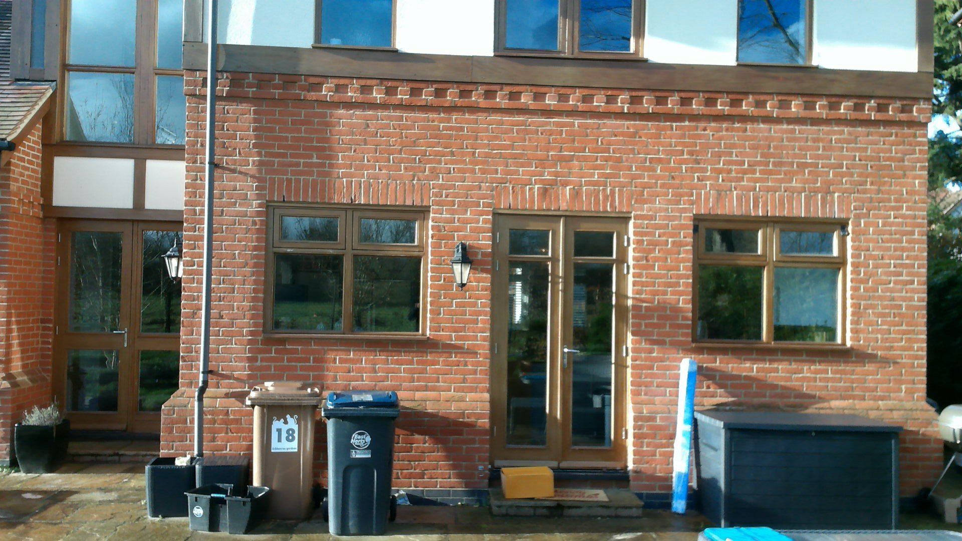 A brick building with a lot of windows and a black trash can in front of it.