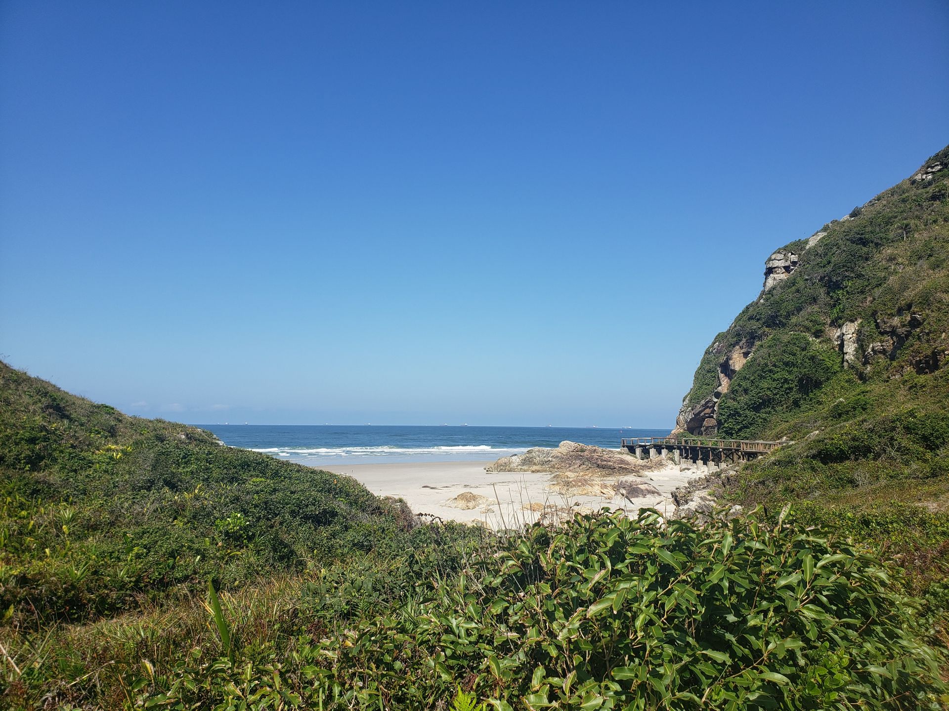 Uma vista de uma praia de um penhasco em um dia ensolarado
