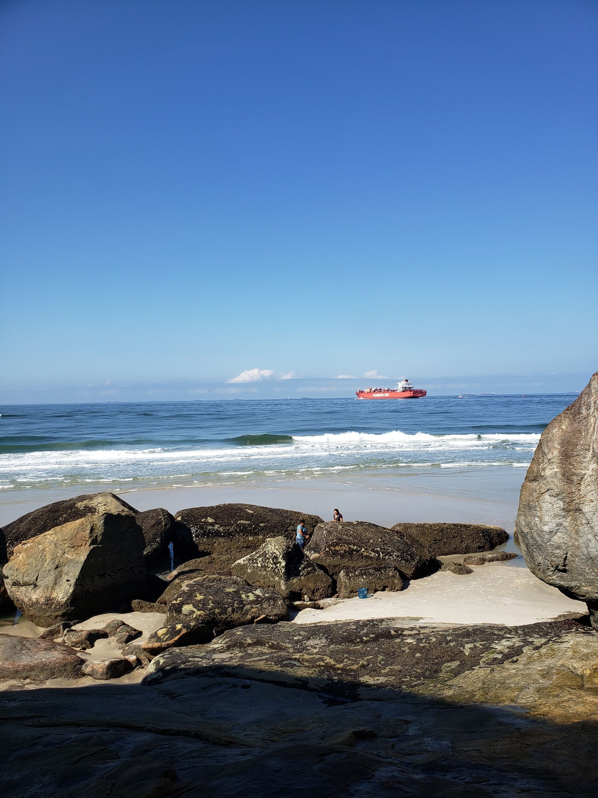 Um barco está flutuando no oceano perto de uma praia rochosa.
