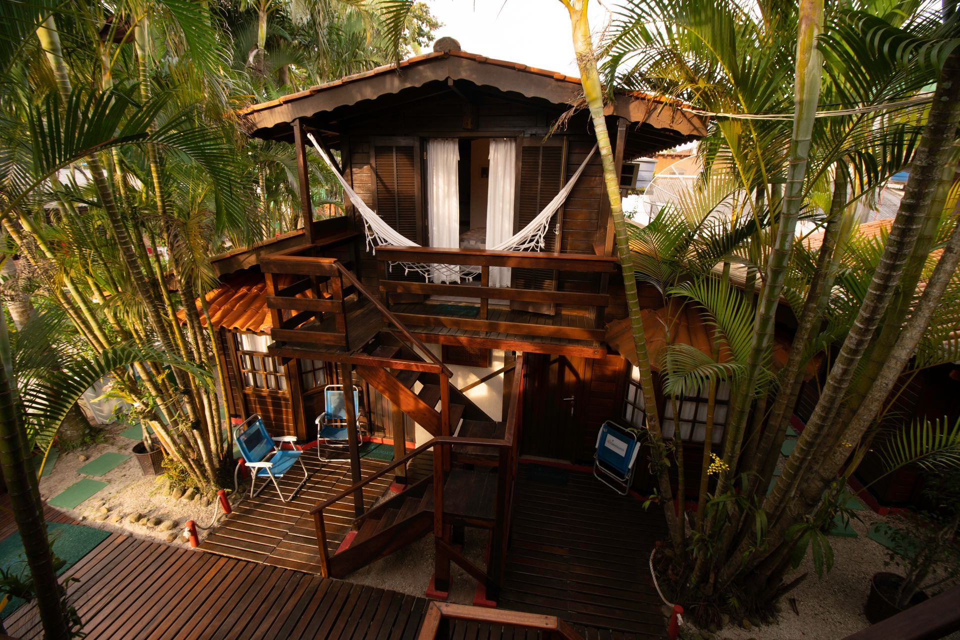 Uma vista aérea de uma casa de madeira cercada por palmeiras