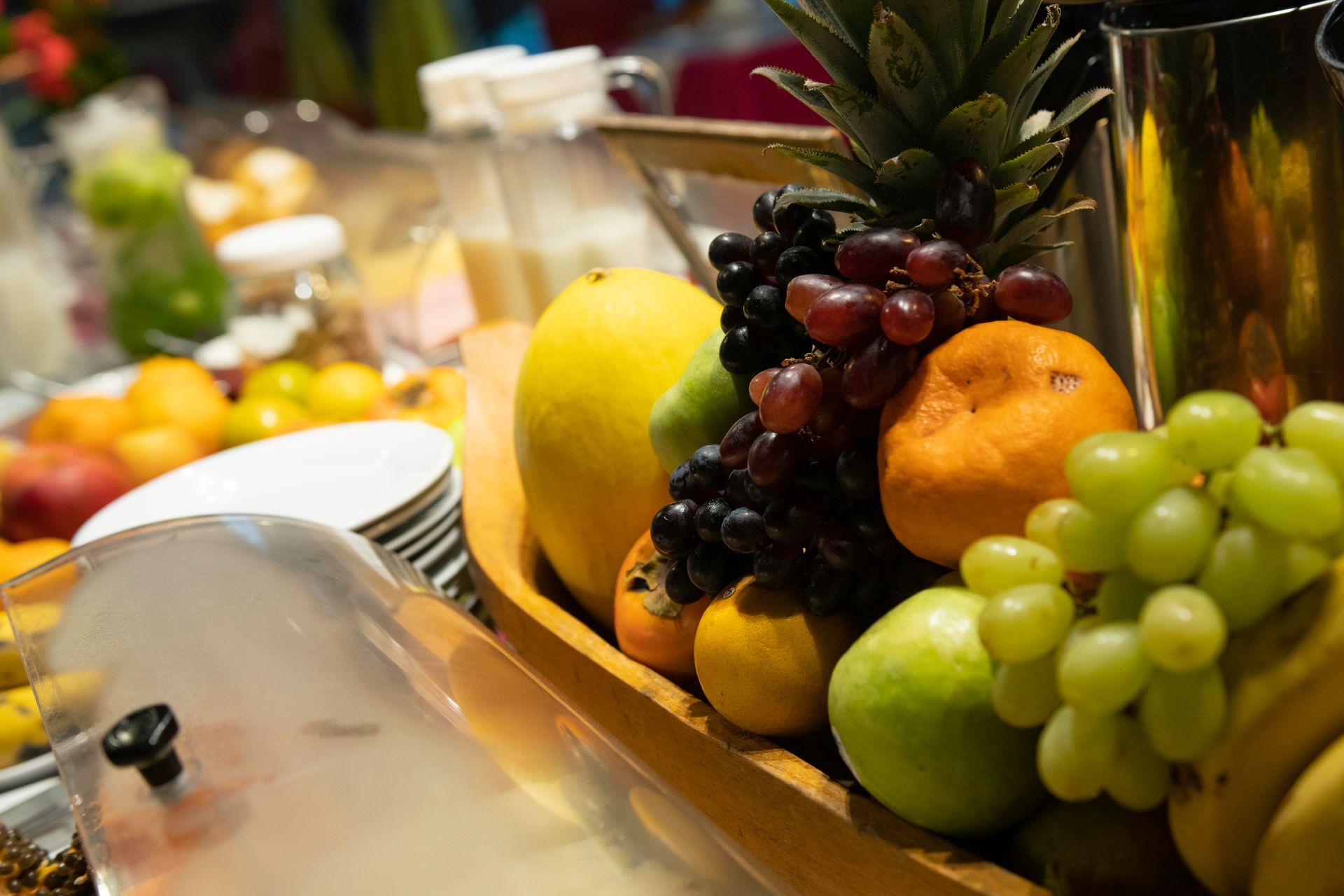 Uma tigela de madeira cheia de frutas está sobre uma mesa.