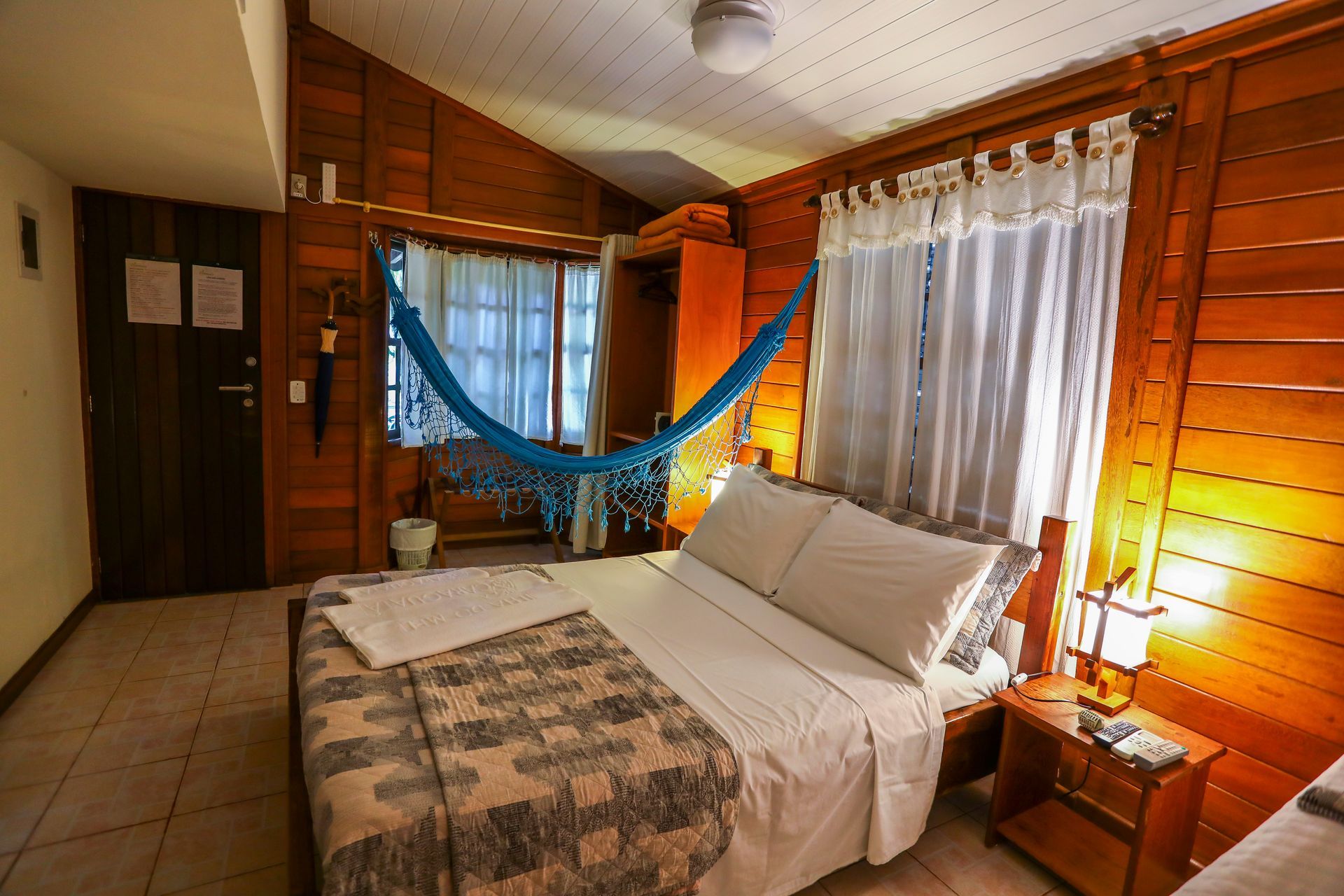 Um quarto com uma cama e uma rede pendurada no teto.