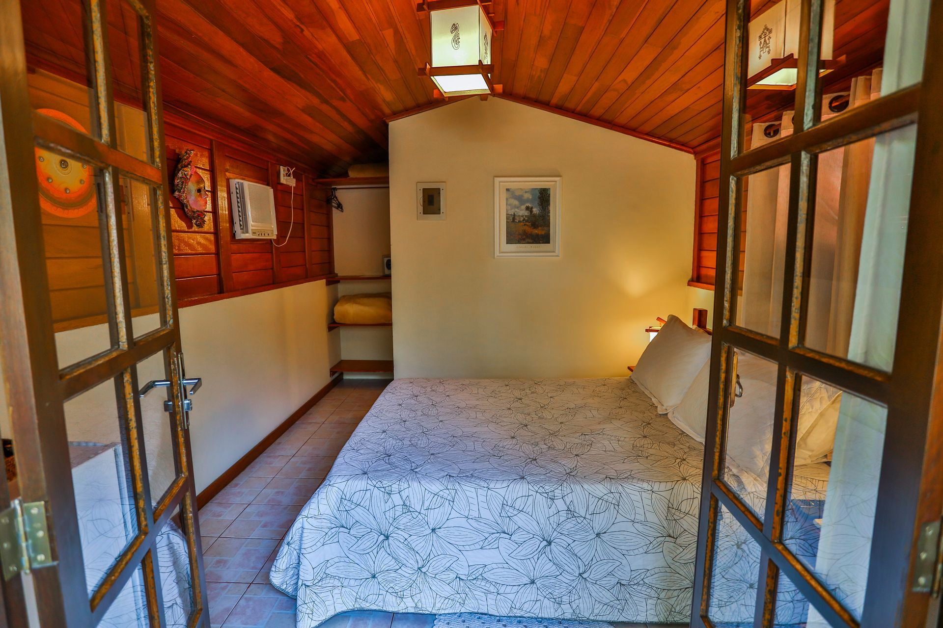 Há uma cama no meio do quarto com teto de madeira.