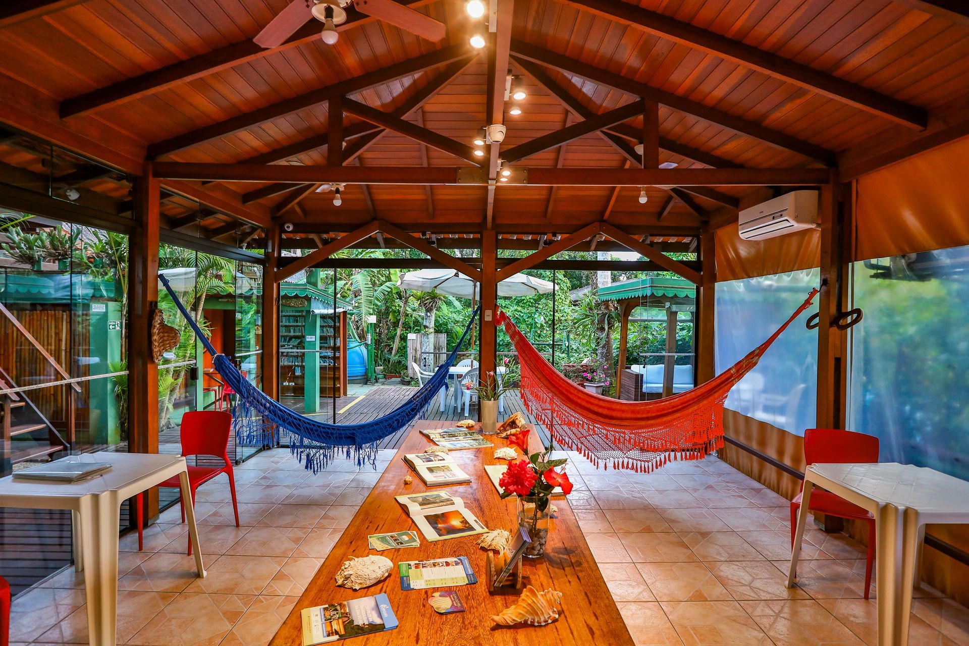 Uma longa mesa de madeira com redes penduradas no teto em uma sala.