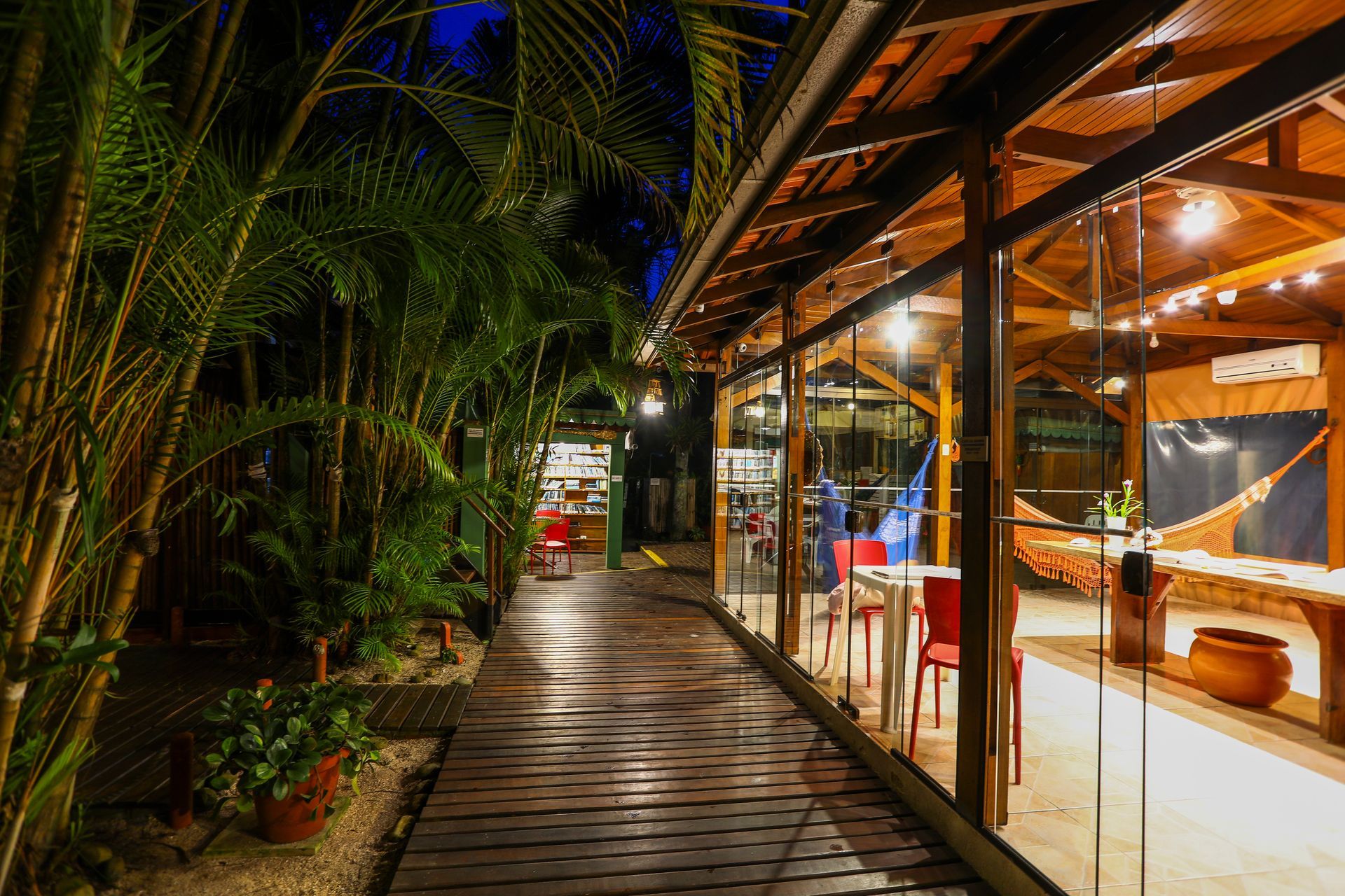 Uma longa passarela de madeira que leva a uma sala com mesas e cadeiras.