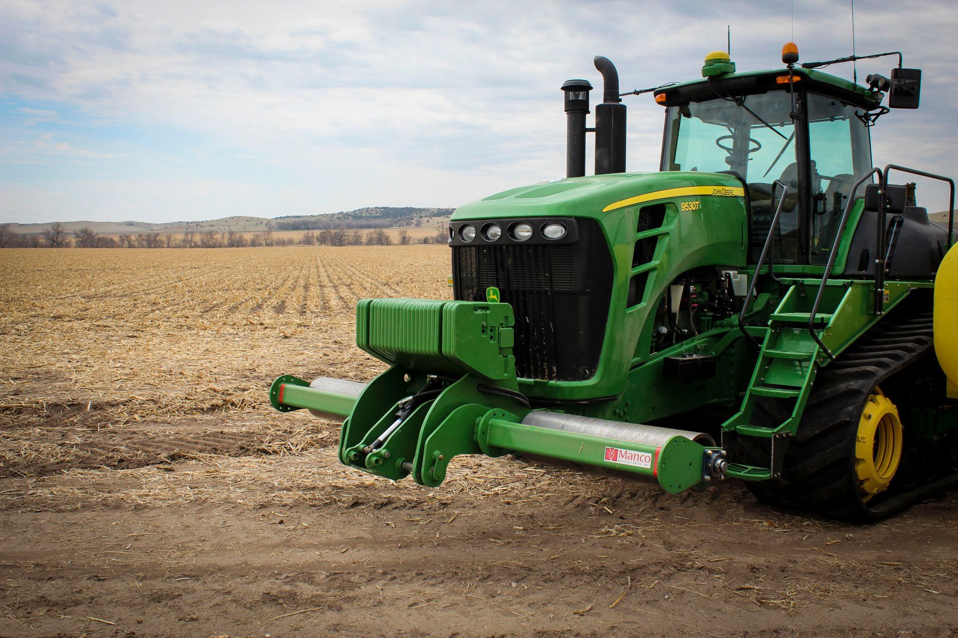 A green john deere tractor with a stalk roller