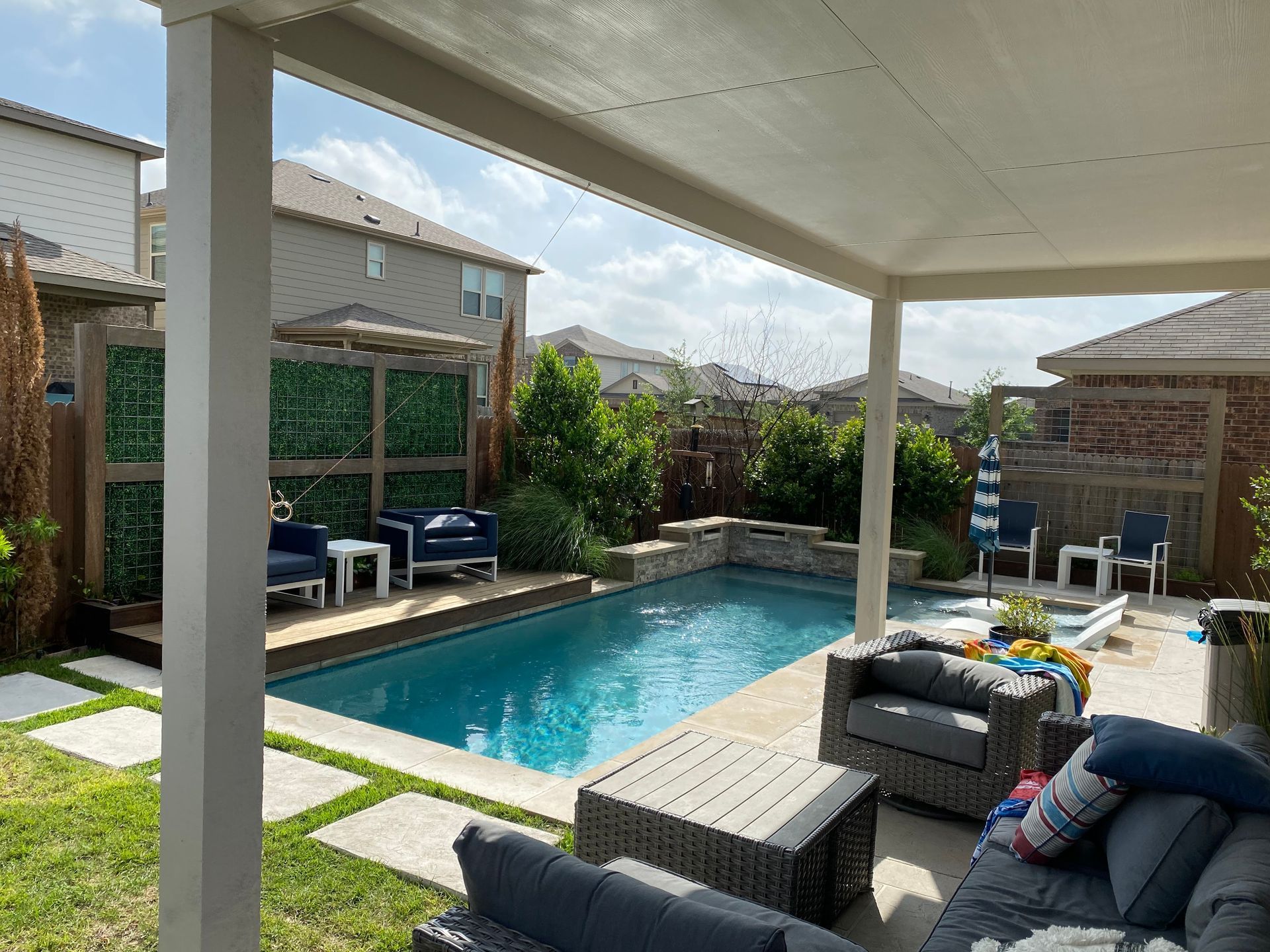 Backyard patio with a swimming pool, outdoor seating, and a covered pergola on a sunny day