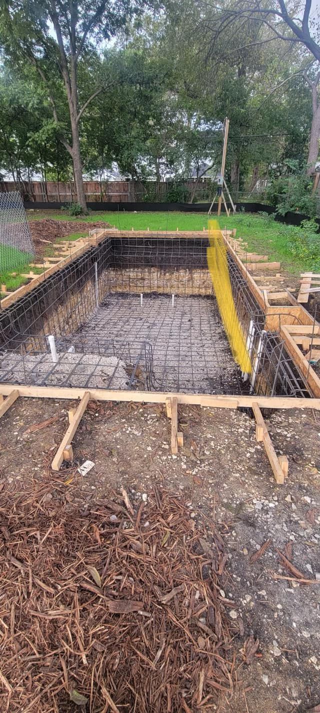 Backyard excavation site with wooden formwork, gravel base, and a yellow ladder