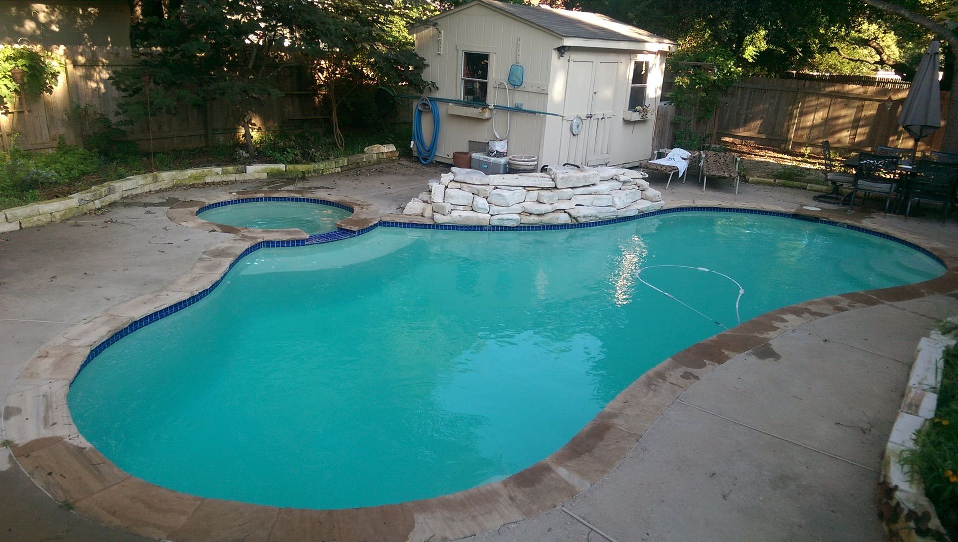 Backyard swimming pool with turquoise water, concrete deck, lounge chairs, and a small shed nearby
