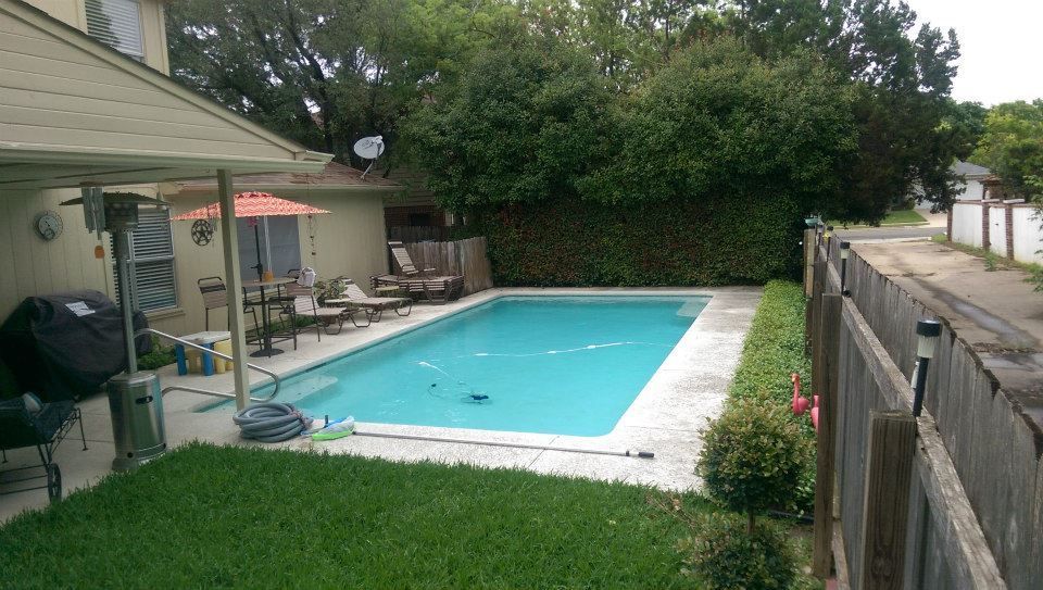 Backyard with a swimming pool, patio seating, and a wooden fence beside a house