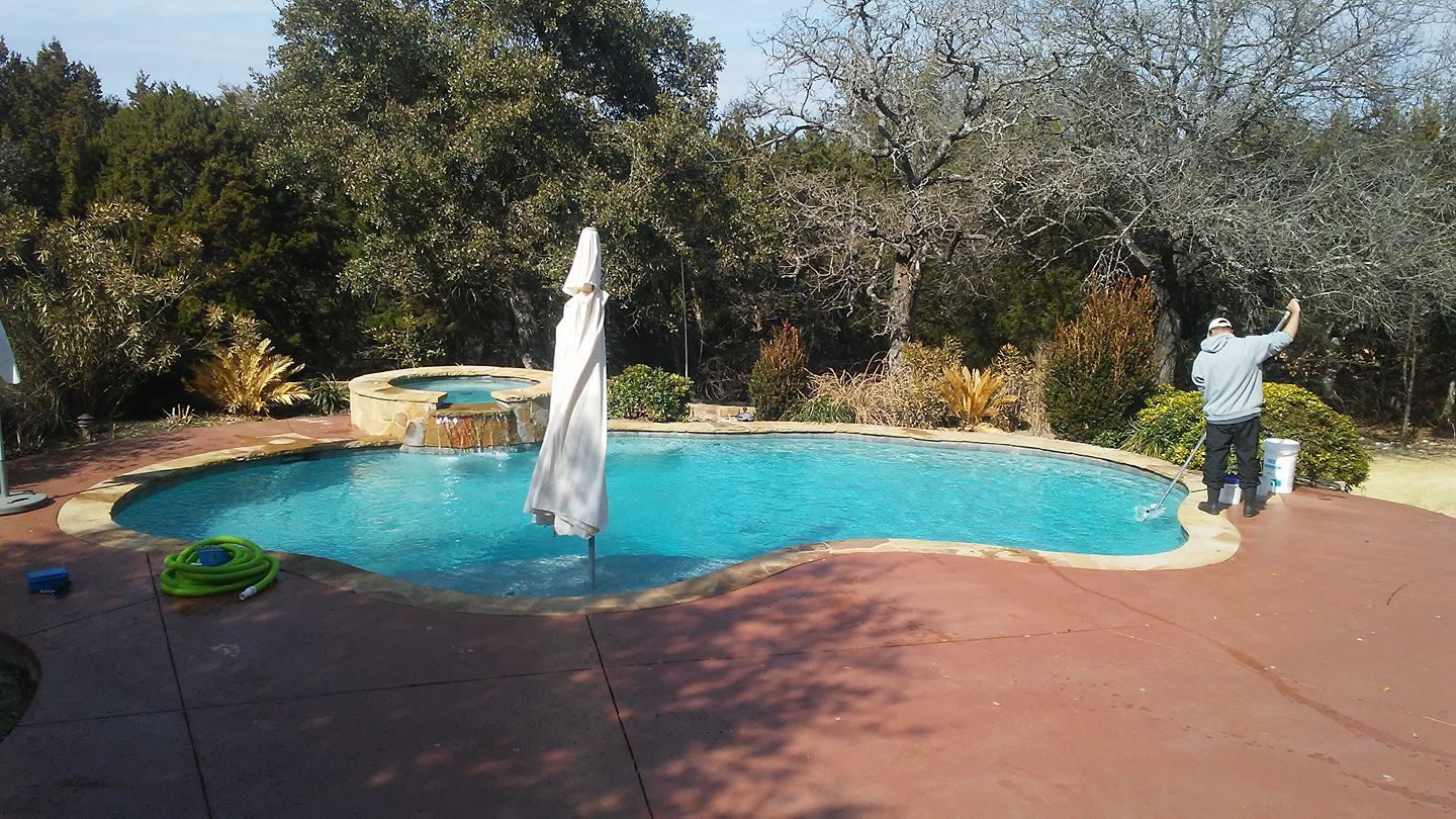 Backyard pool with turquoise water, red deck, and a person standing near the edge