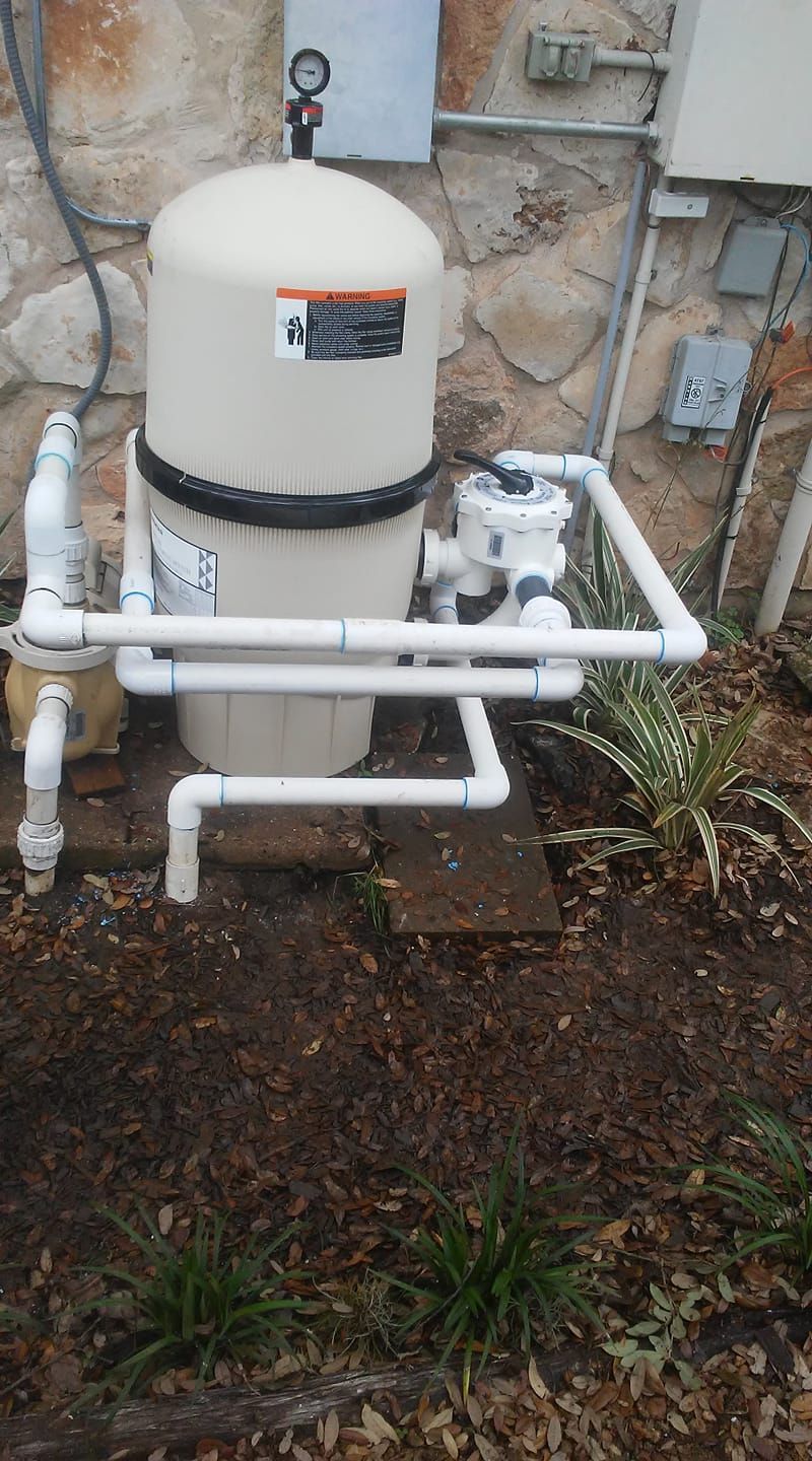 Outdoor pool pump and filtration equipment with white pipes beside a house wall
