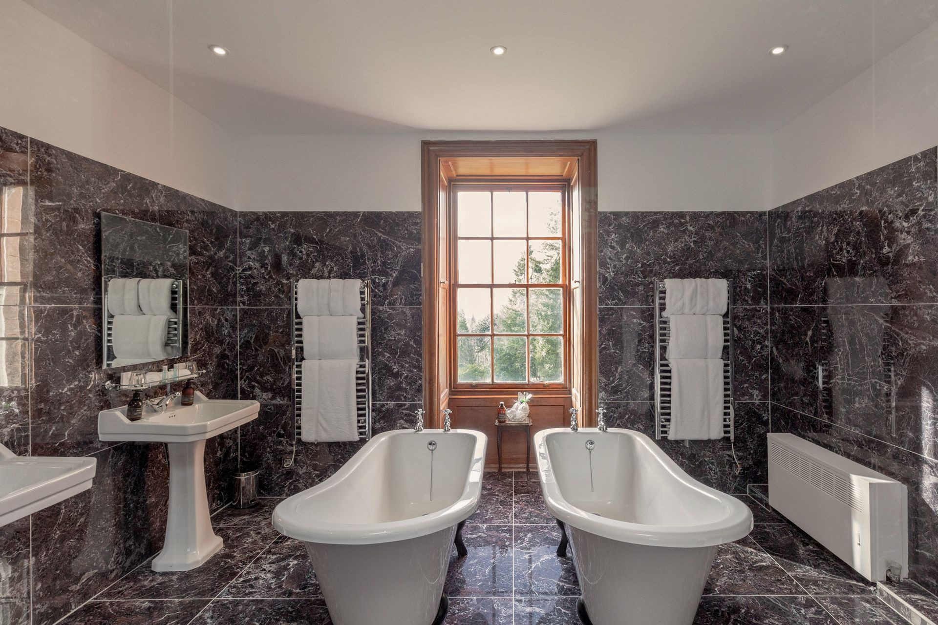 A bathroom with two bathtubs, a sink and a window.