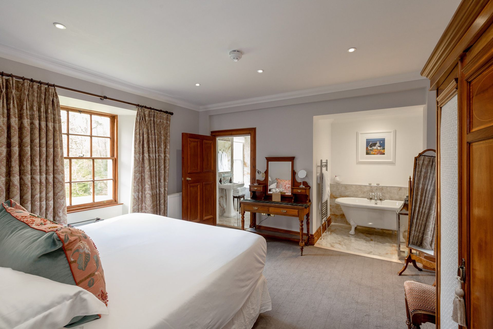 A bedroom with a bed, dresser, mirror and bathtub.