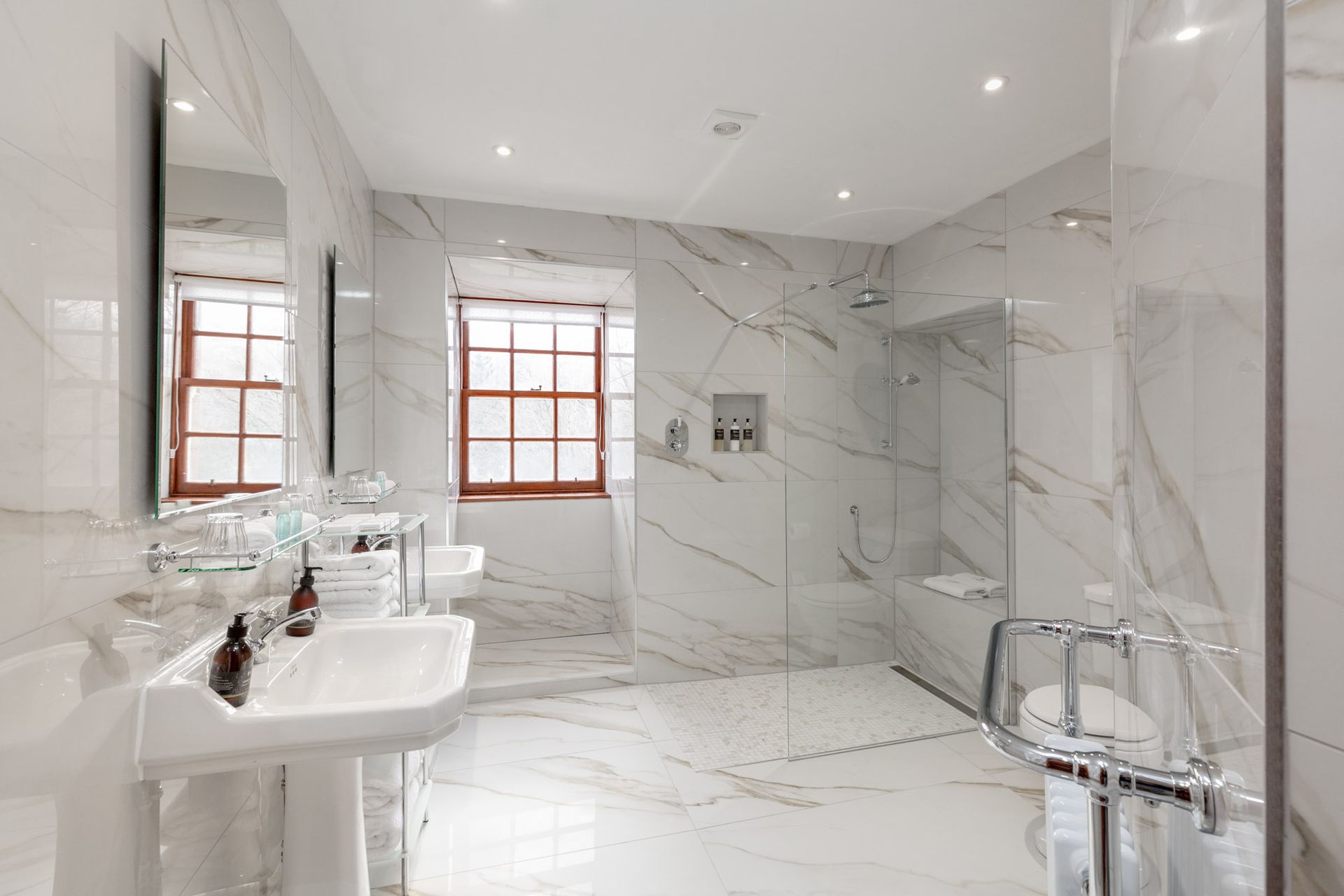 A bathroom with marble tiles and a walk in shower.