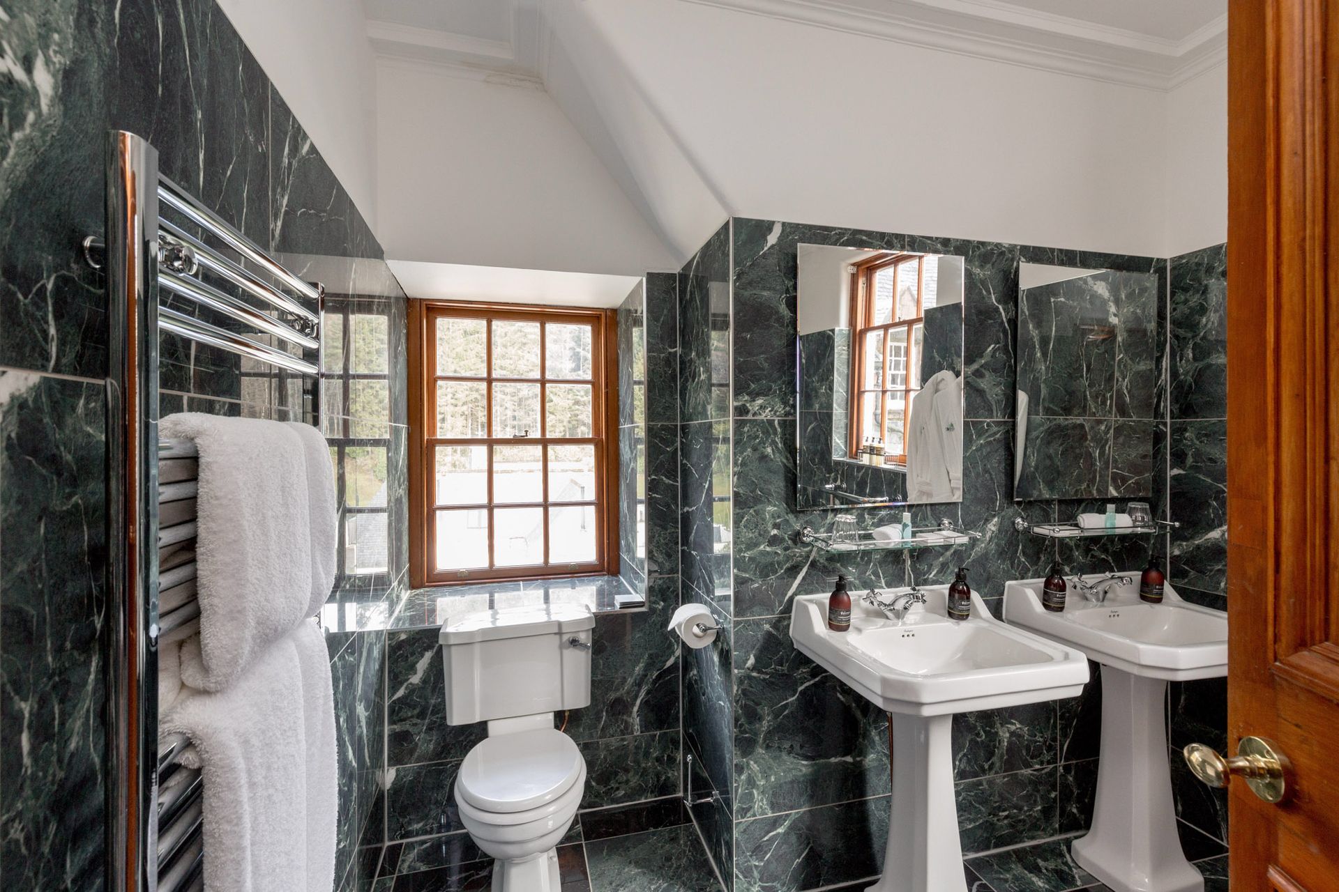 A bathroom with two sinks, a toilet and a window.