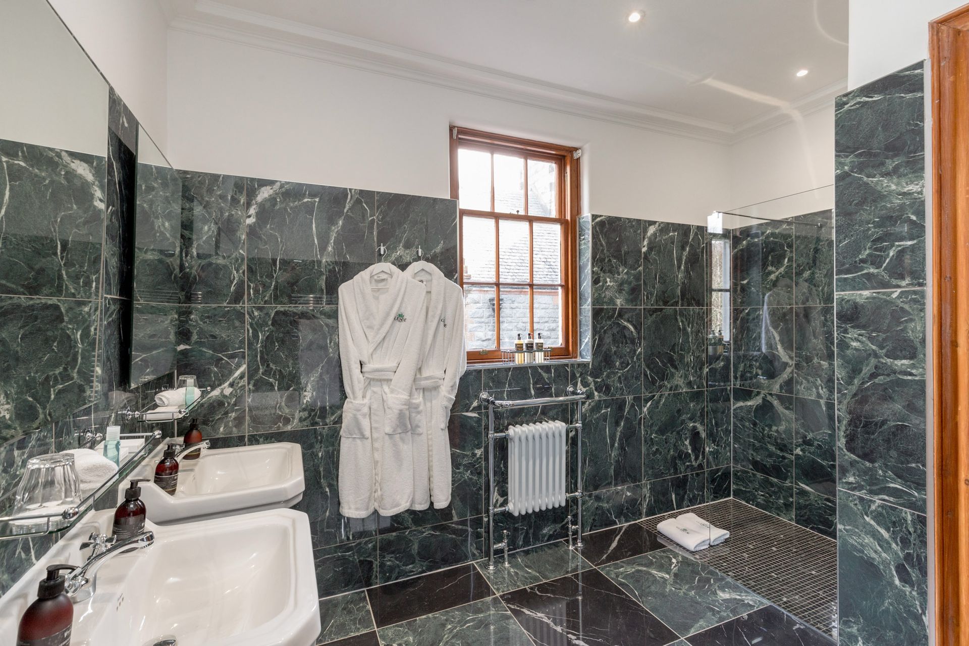 A bathroom with two sinks and a walk in shower.