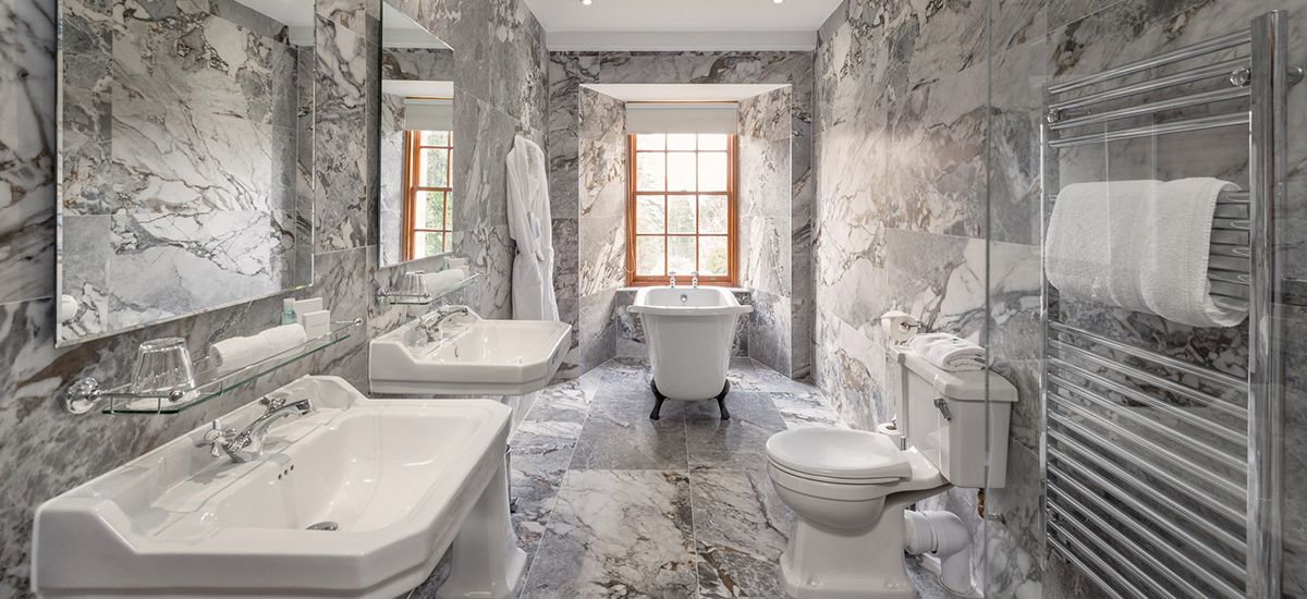 A bathroom with two sinks , a toilet , and a window.