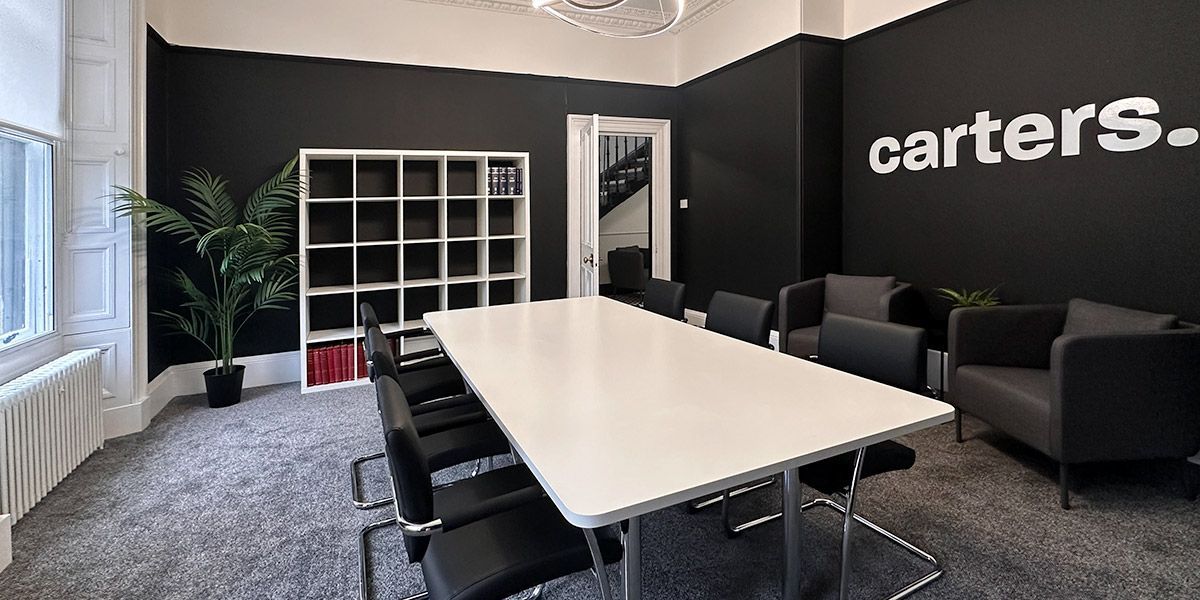 A conference room with a long table and chairs and the word carter 's on the wall.