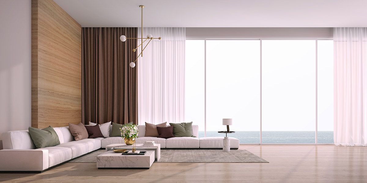 A living room with a large sectional couch , coffee table , and large windows.
