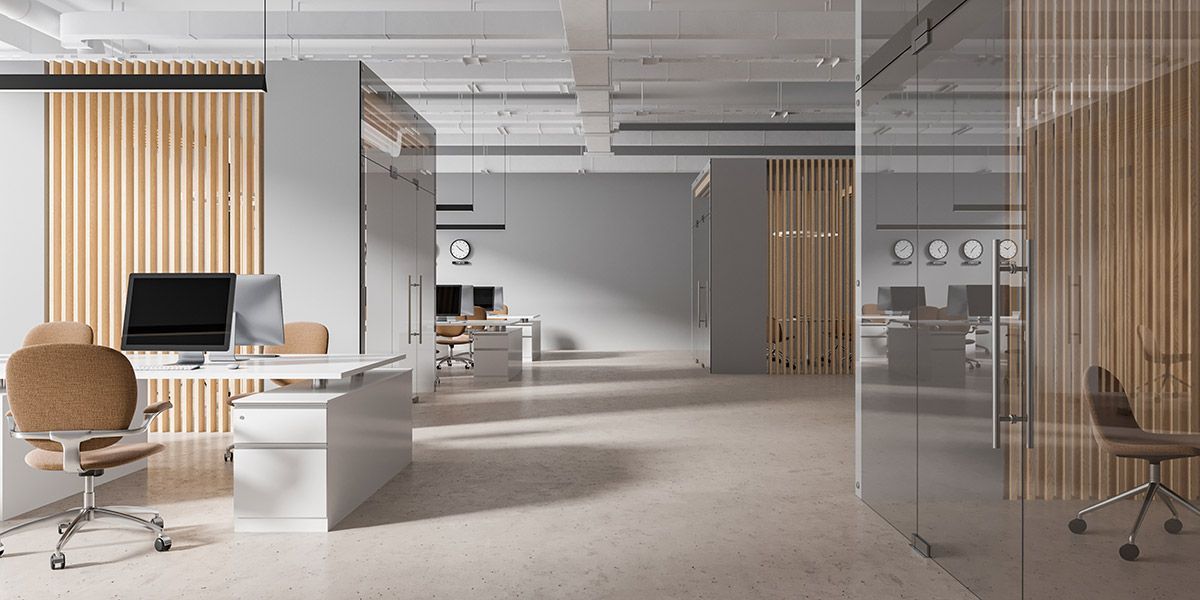 A modern office with a lot of glass walls and a computer on a desk.