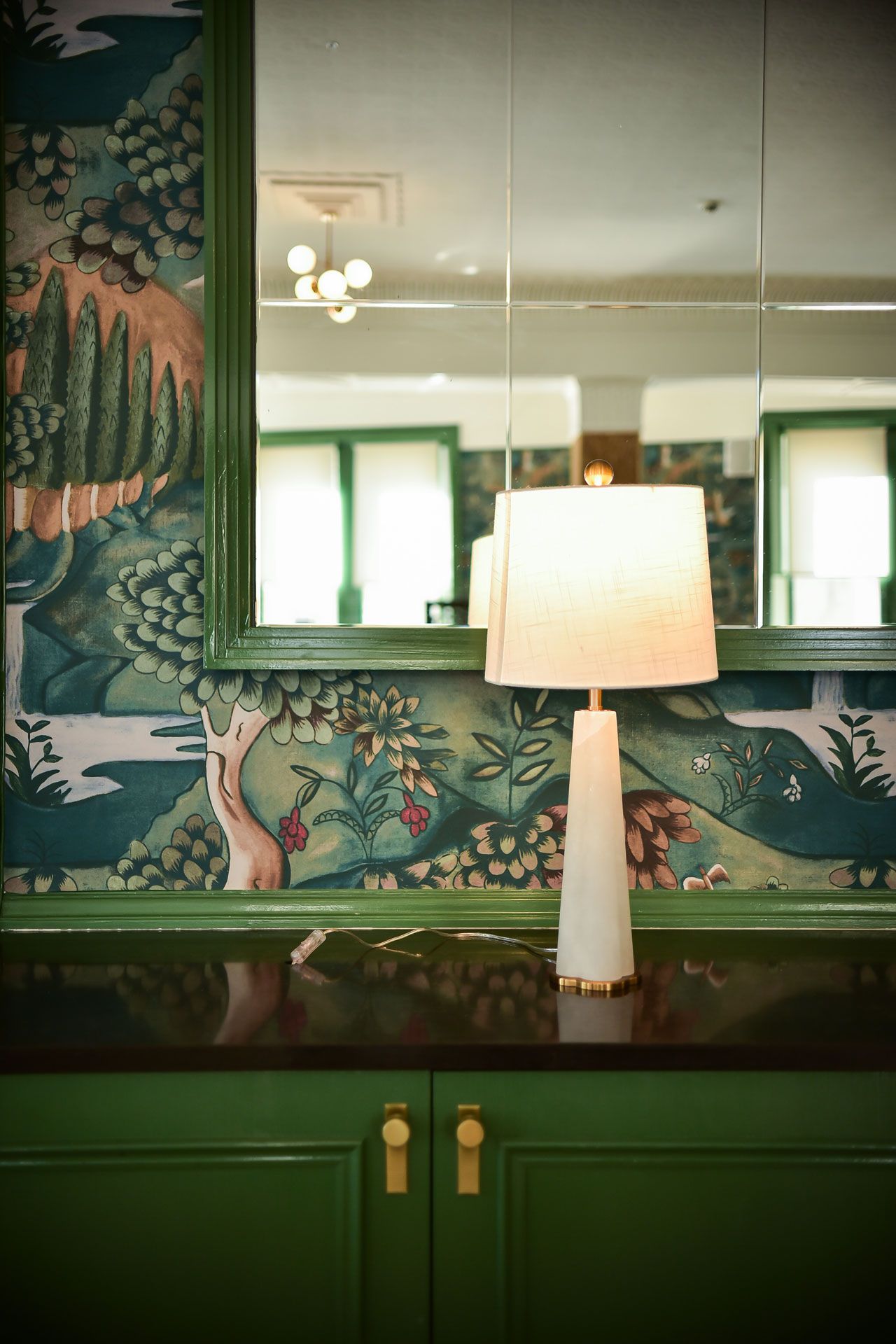 A lamp is sitting on a counter in front of a mirror.