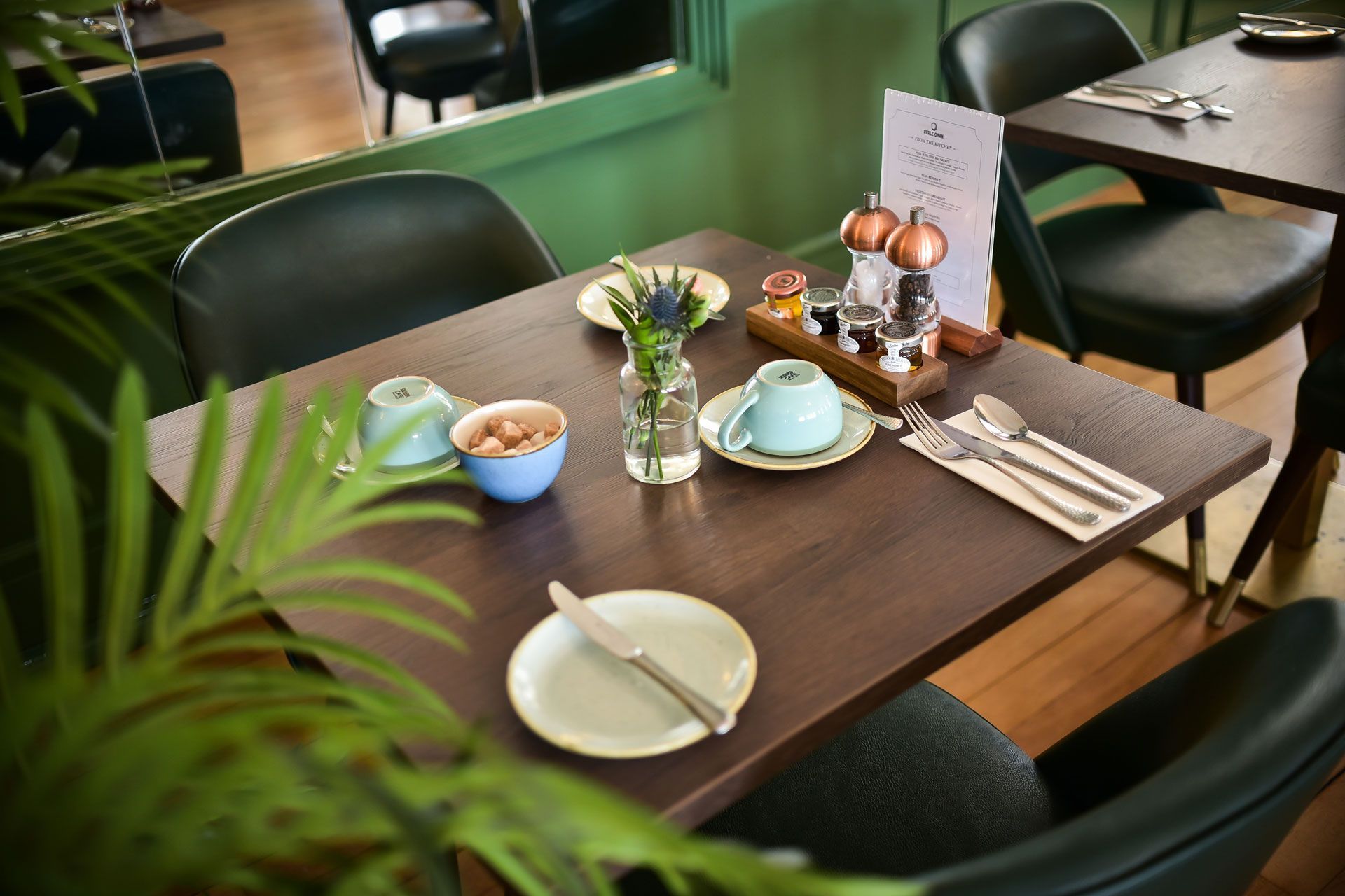 A table with plates, cups and silverware on it in a restaurant.