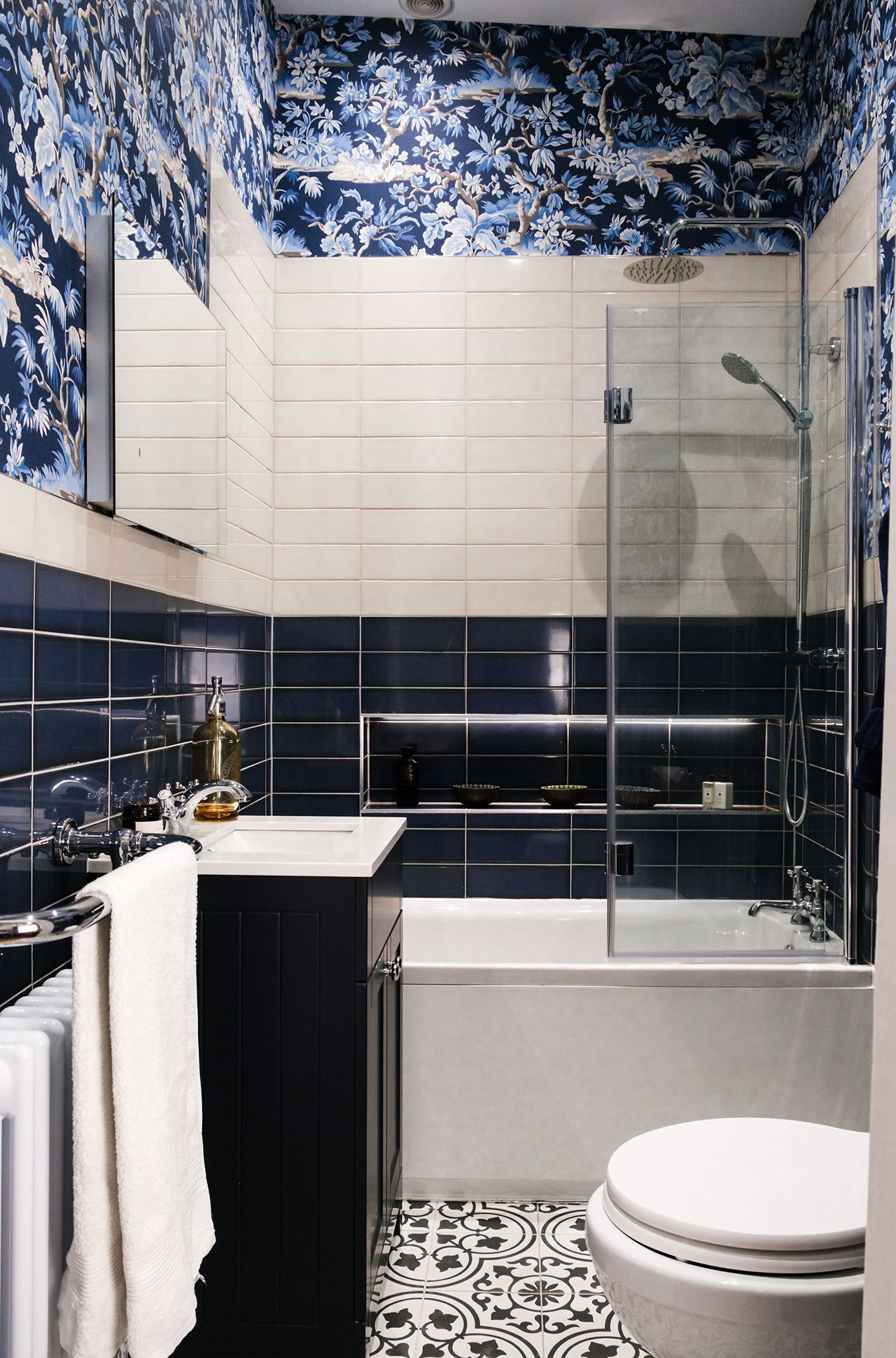 Blue and white tiled bathroom with a tub, shower and patterned floor.