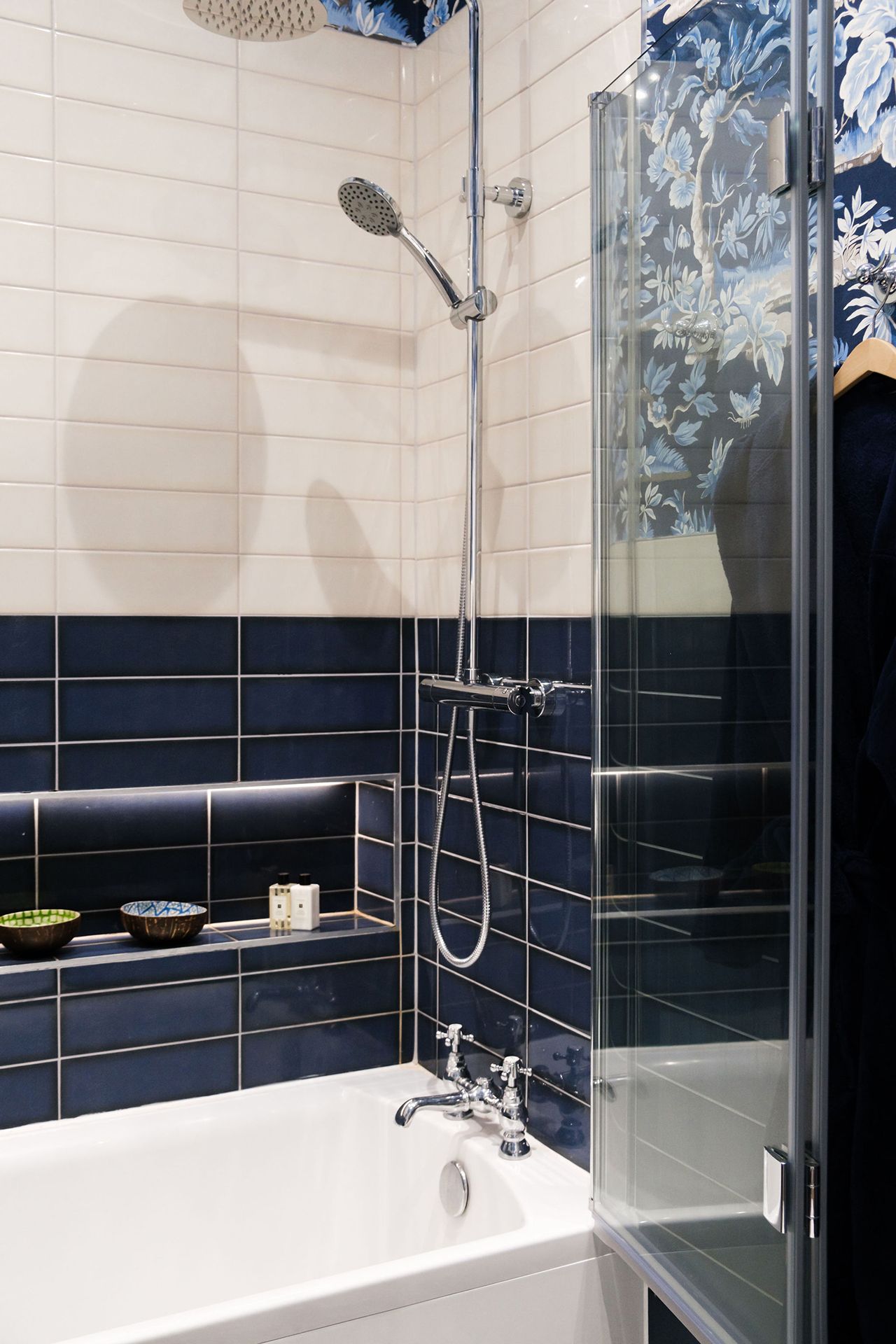 Bathroom with white and blue tiled walls, shower, bathtub and glass shower door.