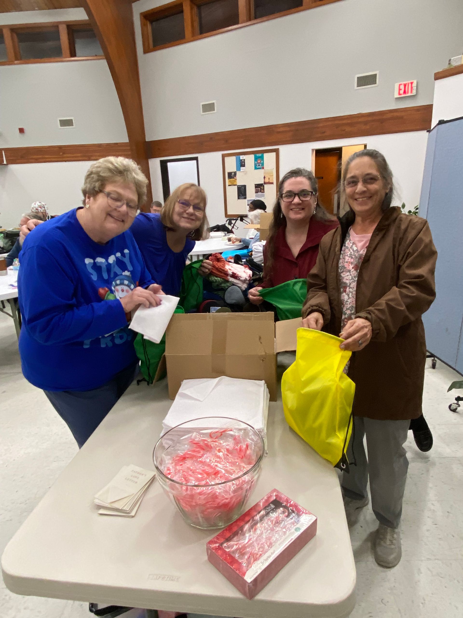 A group of people are standing around a table filled with cans of food.