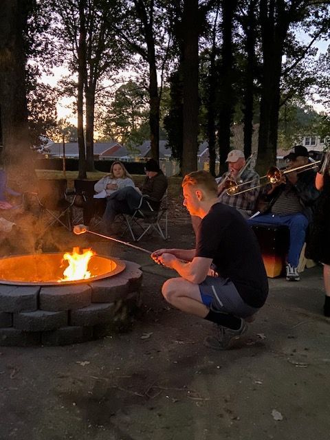 A group of people are roasting marshmallows over a fire pit.