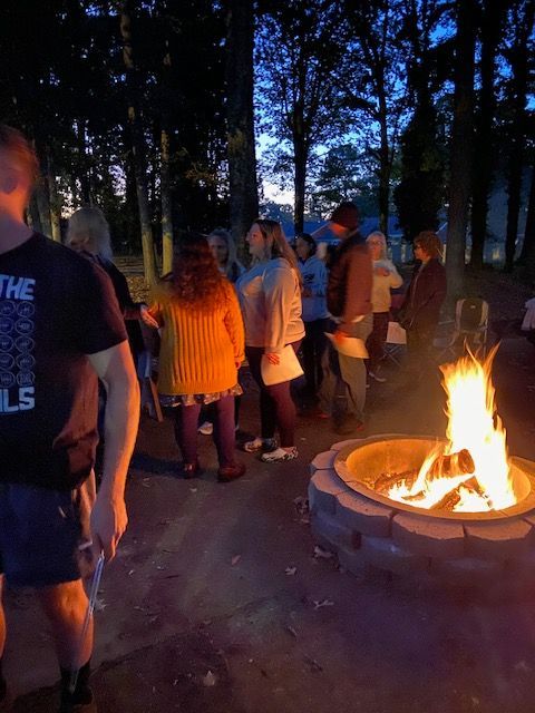 A group of people are standing around a fire pit.