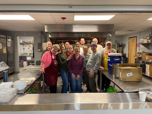 A group of people are standing around a table filled with cans of food.