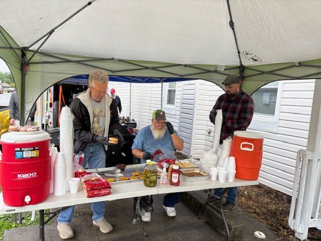 A group of people are standing around a table filled with cans of food.