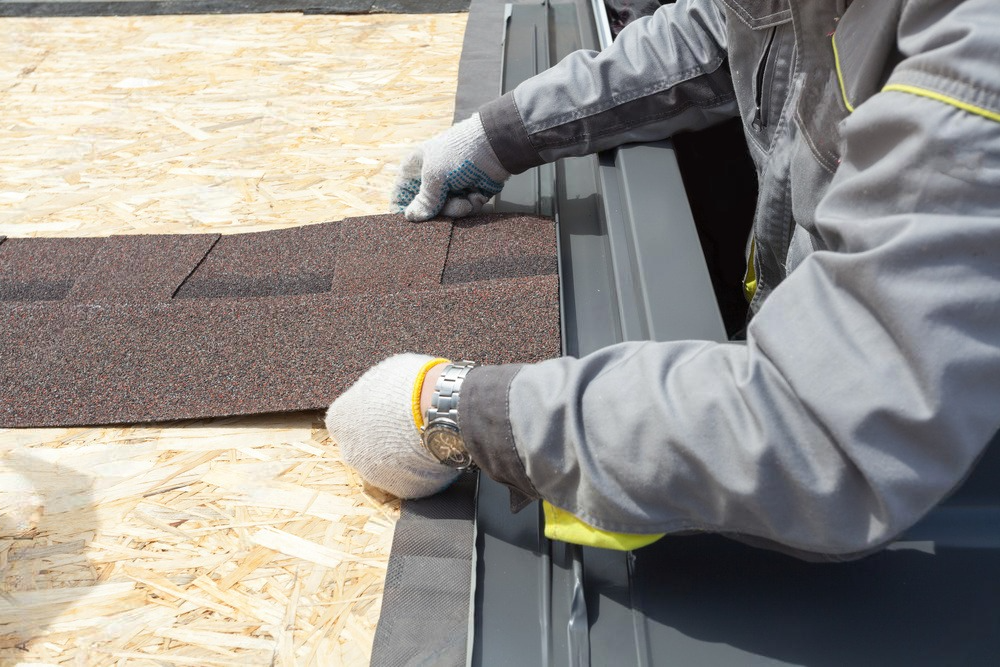 a man is installing shingles on a roof .