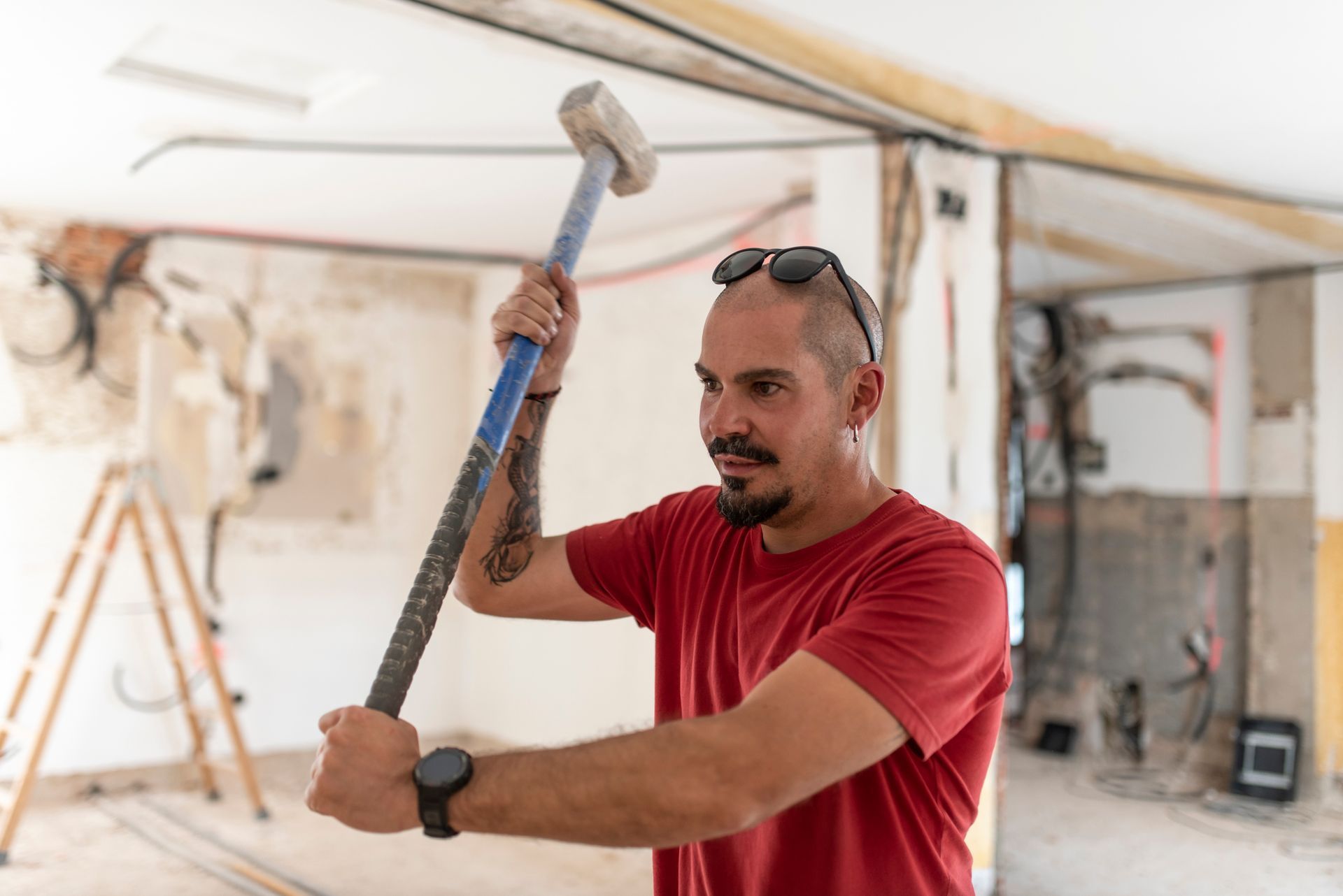 Person holding a sledgehammer during home renovation work.