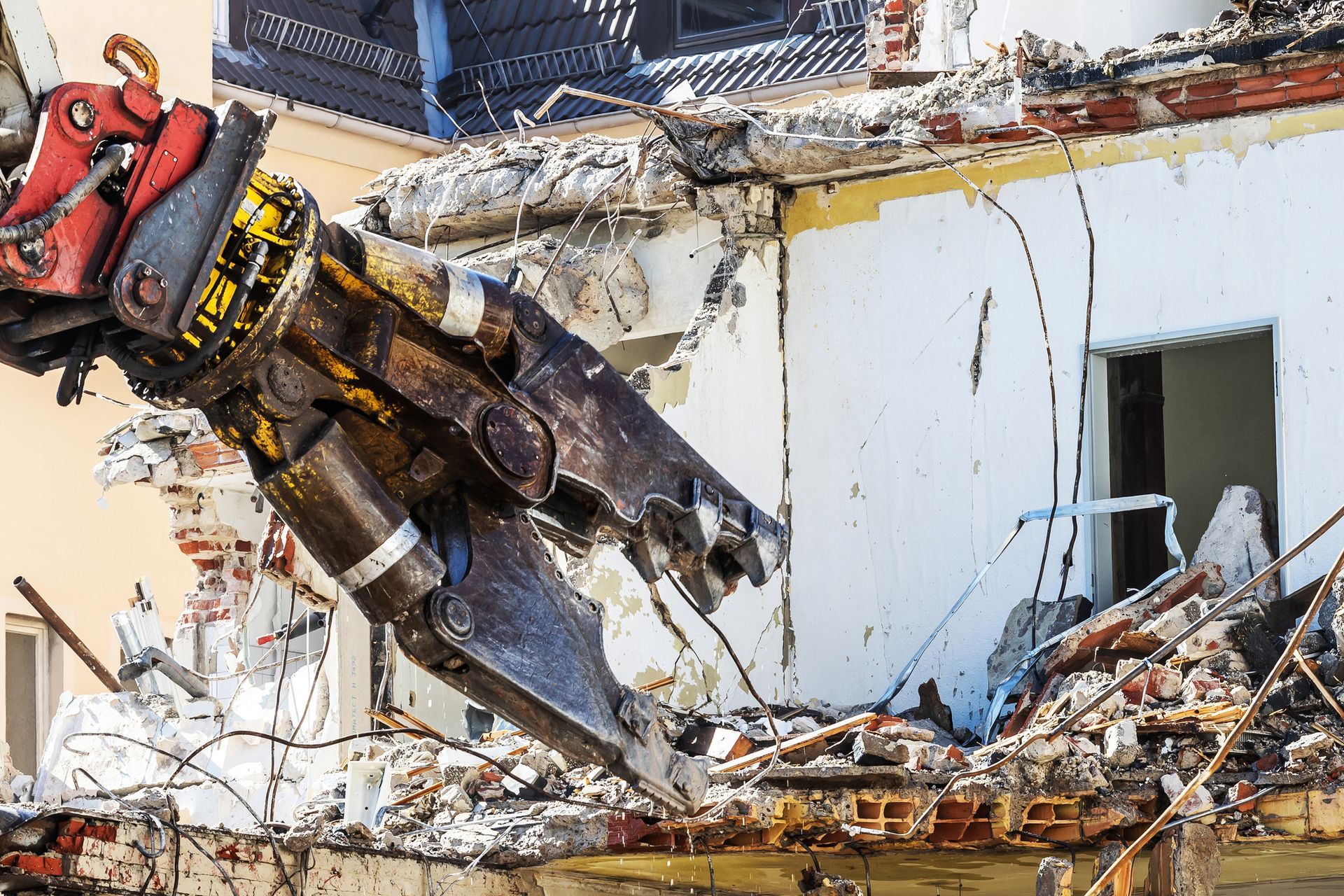 A large demolition machine breaking steel, stone, and concrete from a building structure