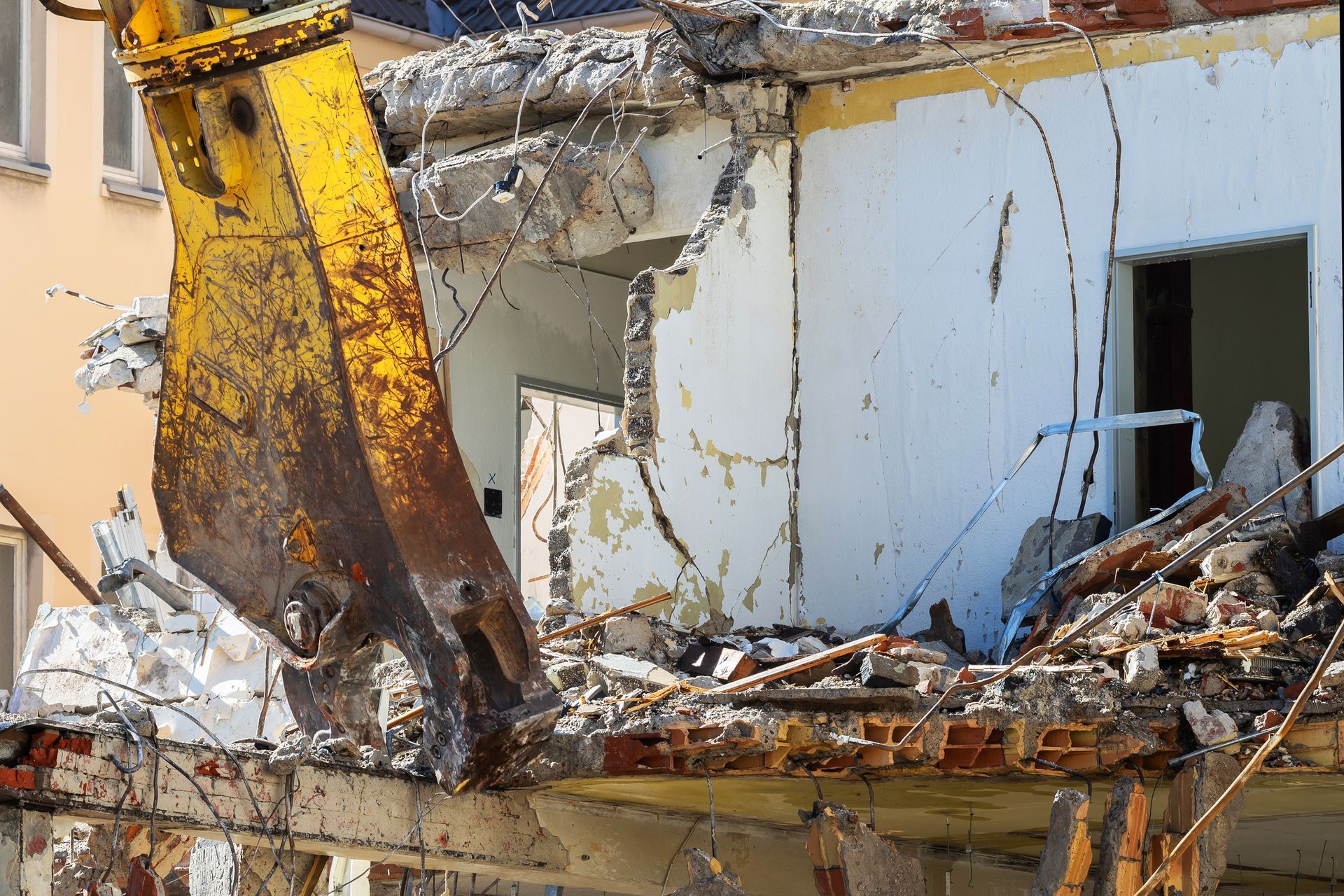 A demolition machine breaking steel, stone, and concrete from a partially collapsed structure A demolition machine breaking steel, stone, and concrete from a partially collapsed structure