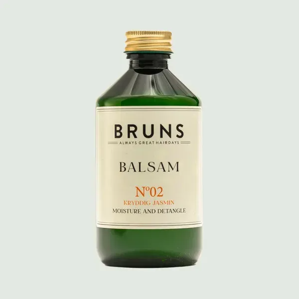 Een fles BRUNS Balsam No. 02 haarconditioner in een groene glazen fles met een gouden dop op een lichte achtergrond.