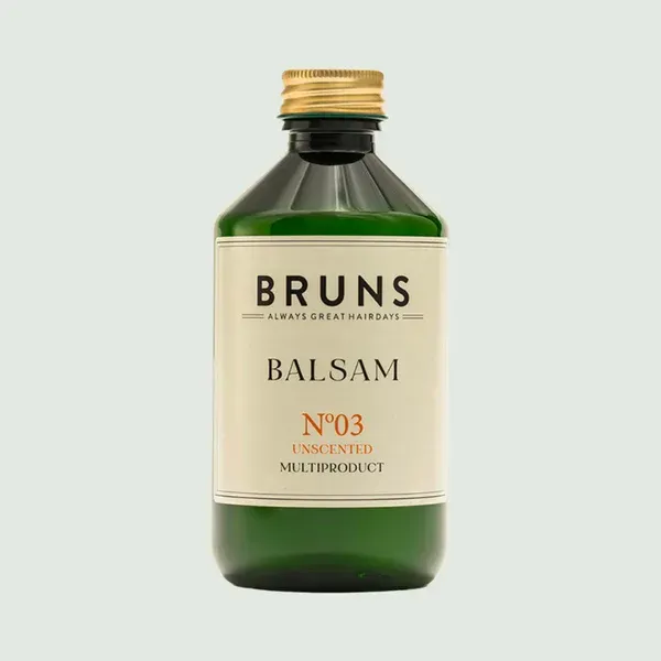 Een groene glazen fles Bruns No. 03 ongeparfumeerde haarbalsem met een gouden dop en een crèmekleurig etiket.