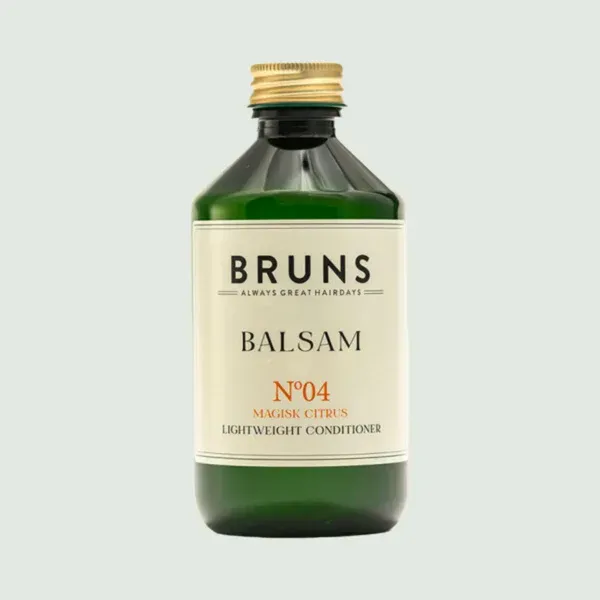 Een groene, cilindrische fles Bruns No. 04 Balsam lichte conditioner met een gouden dop en een wit etiket.